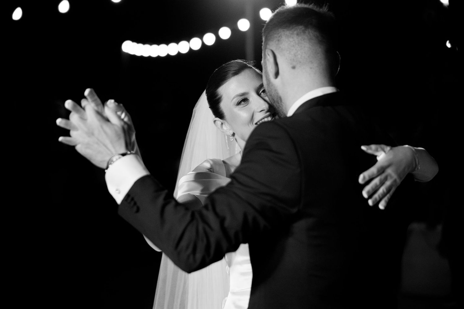 Black and white photos capturing intimate wedding moments under string lights.