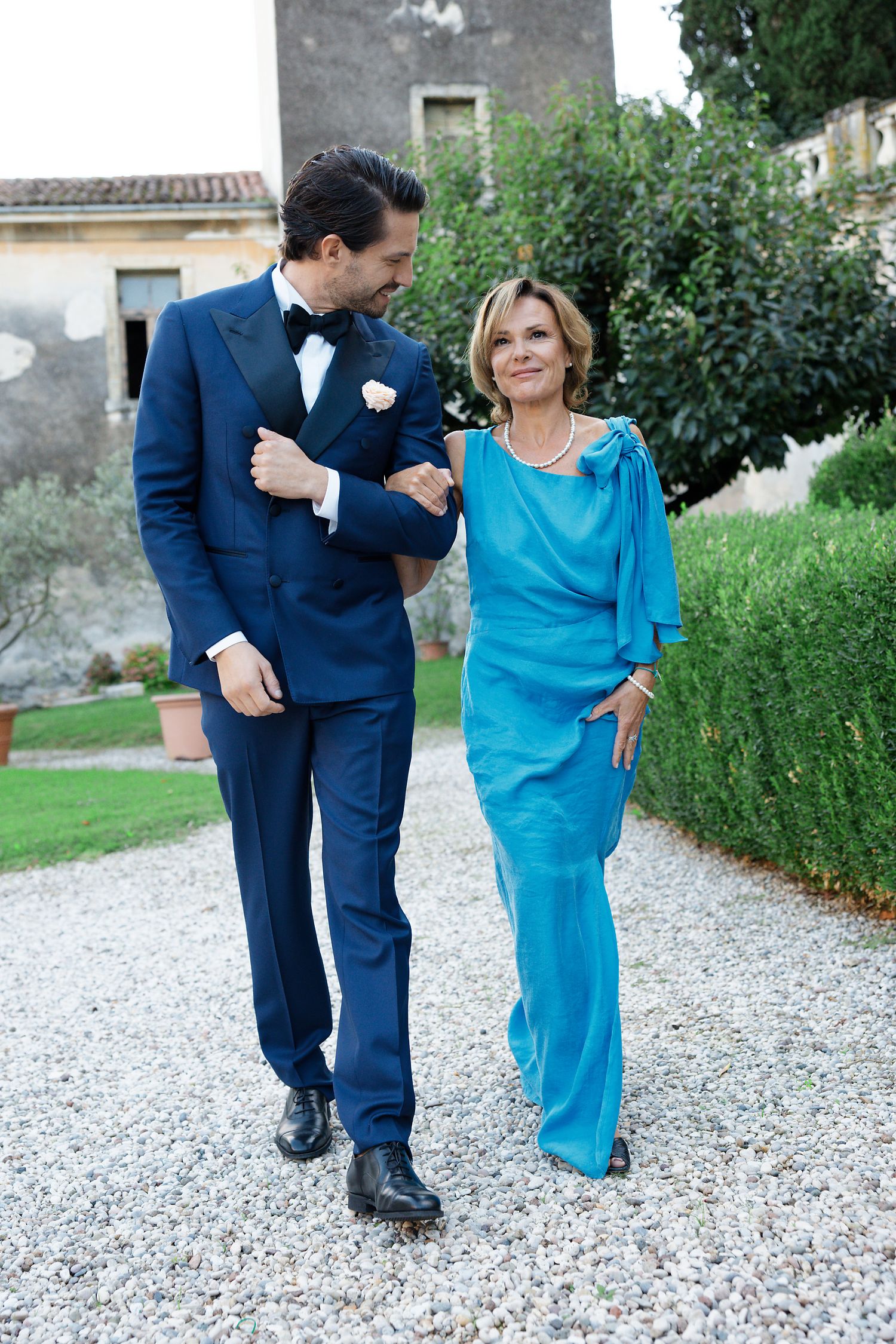 Formal outdoor portrait on gravel path featuring navy tuxedo and turquoise evening gown.