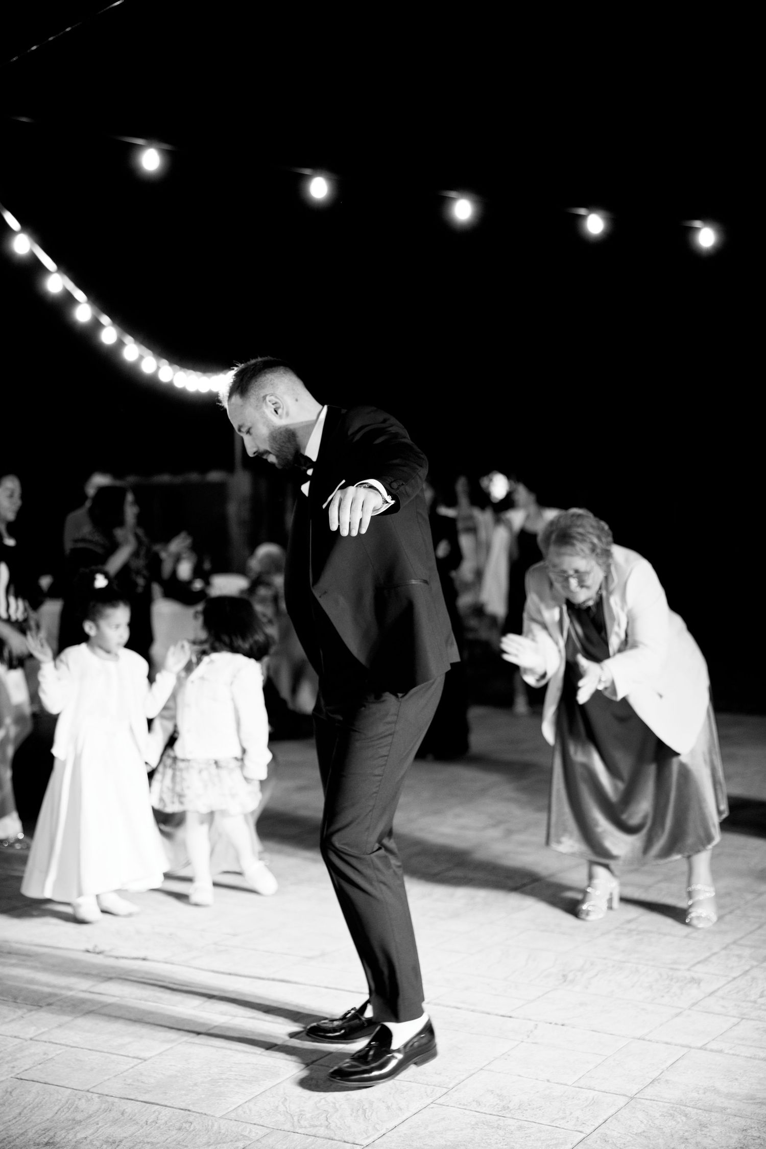 A black and white photo captures guests dancing on a festive dance floor.