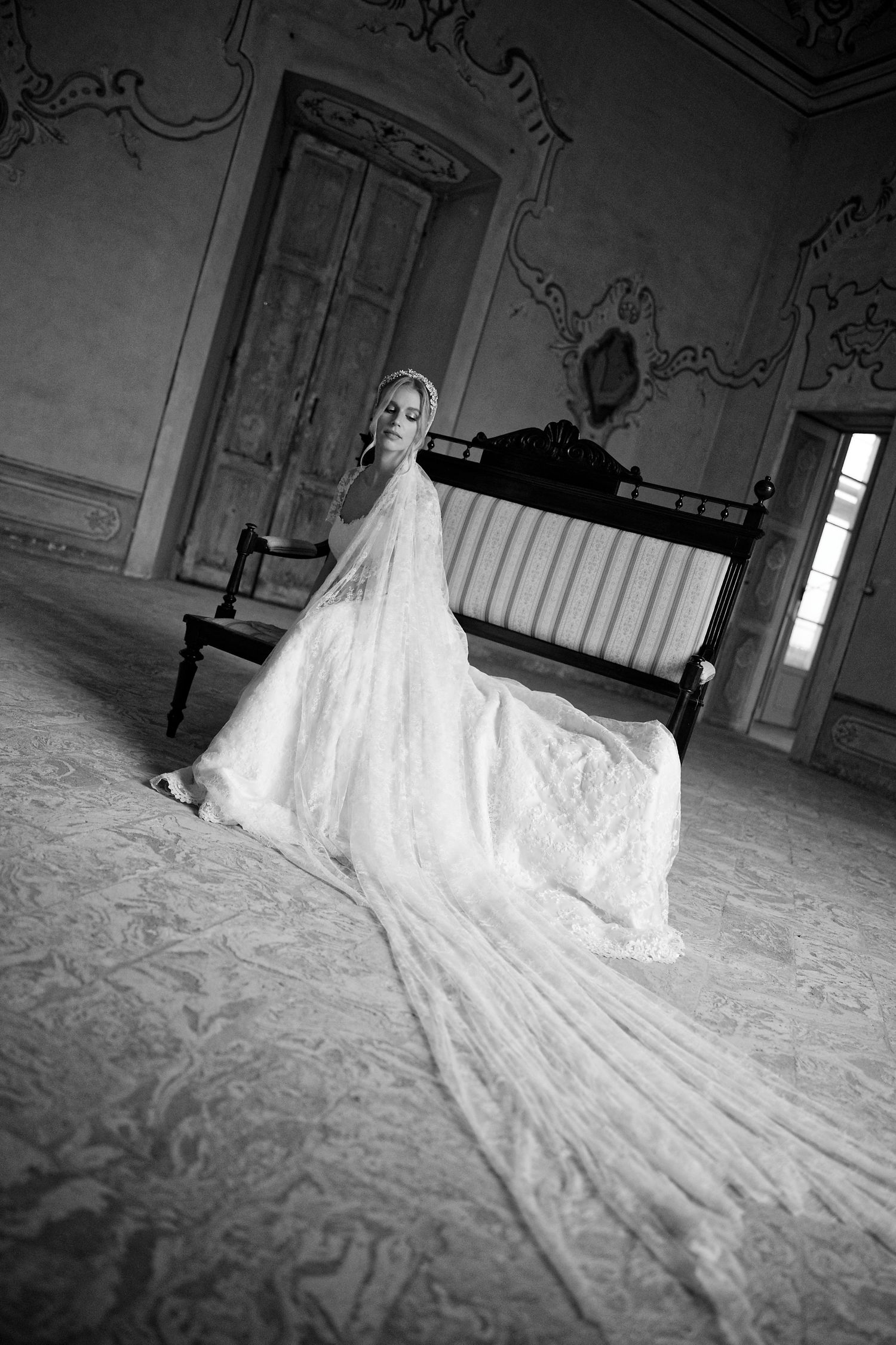 Black and white bridal portrait showcasing flowing train in elegant vintage room.