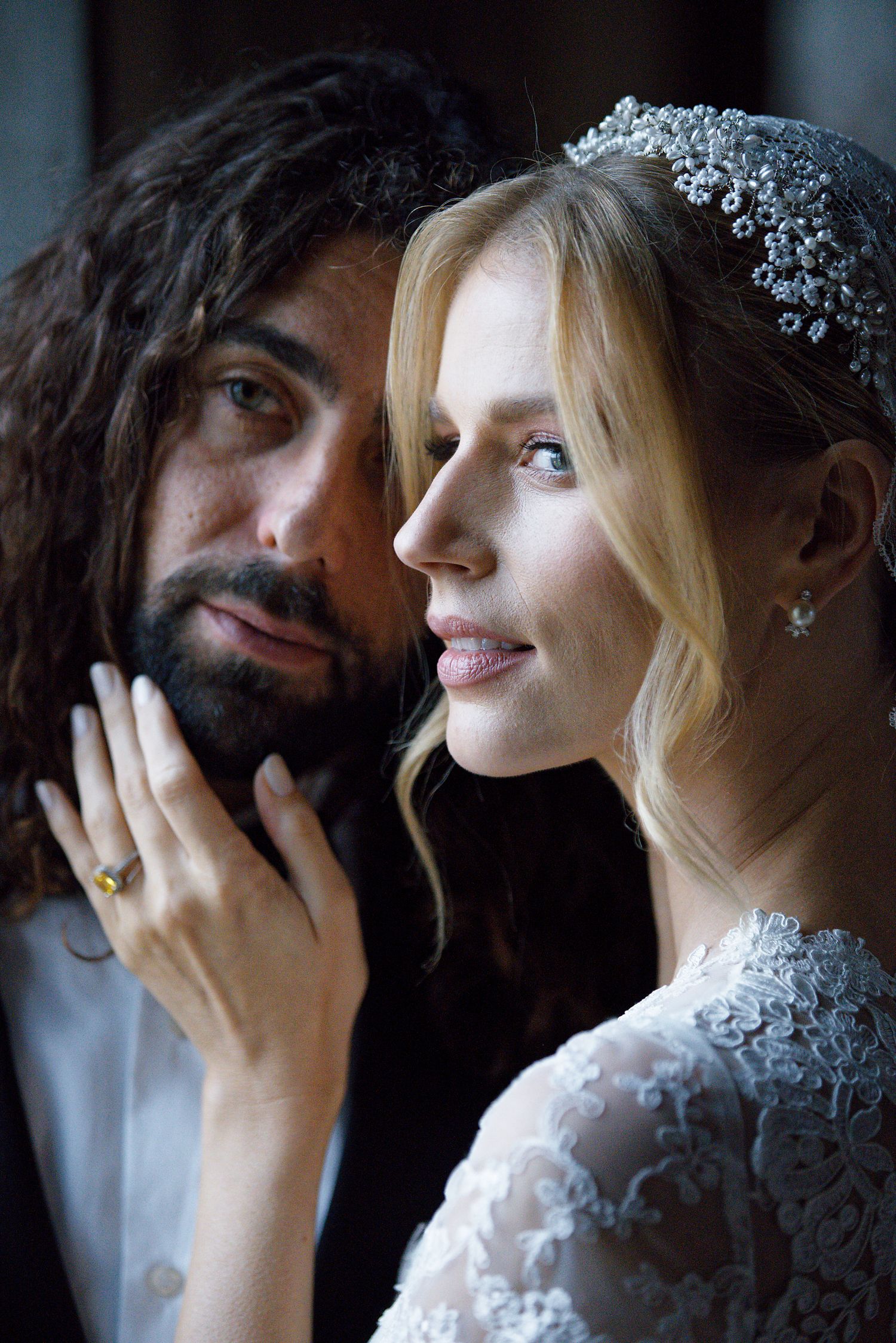 An intimate wedding portrait captures a tender moment between newlyweds in soft lighting.