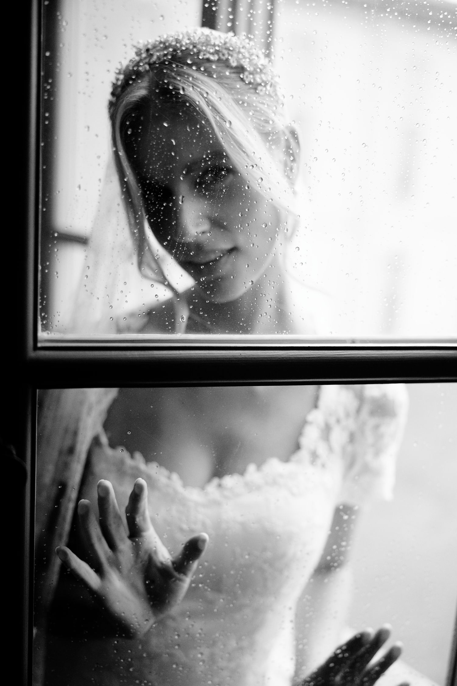 Artistic black and white photograph showing a dreamy silhouette behind frosted glass with raindrops or condensation.
