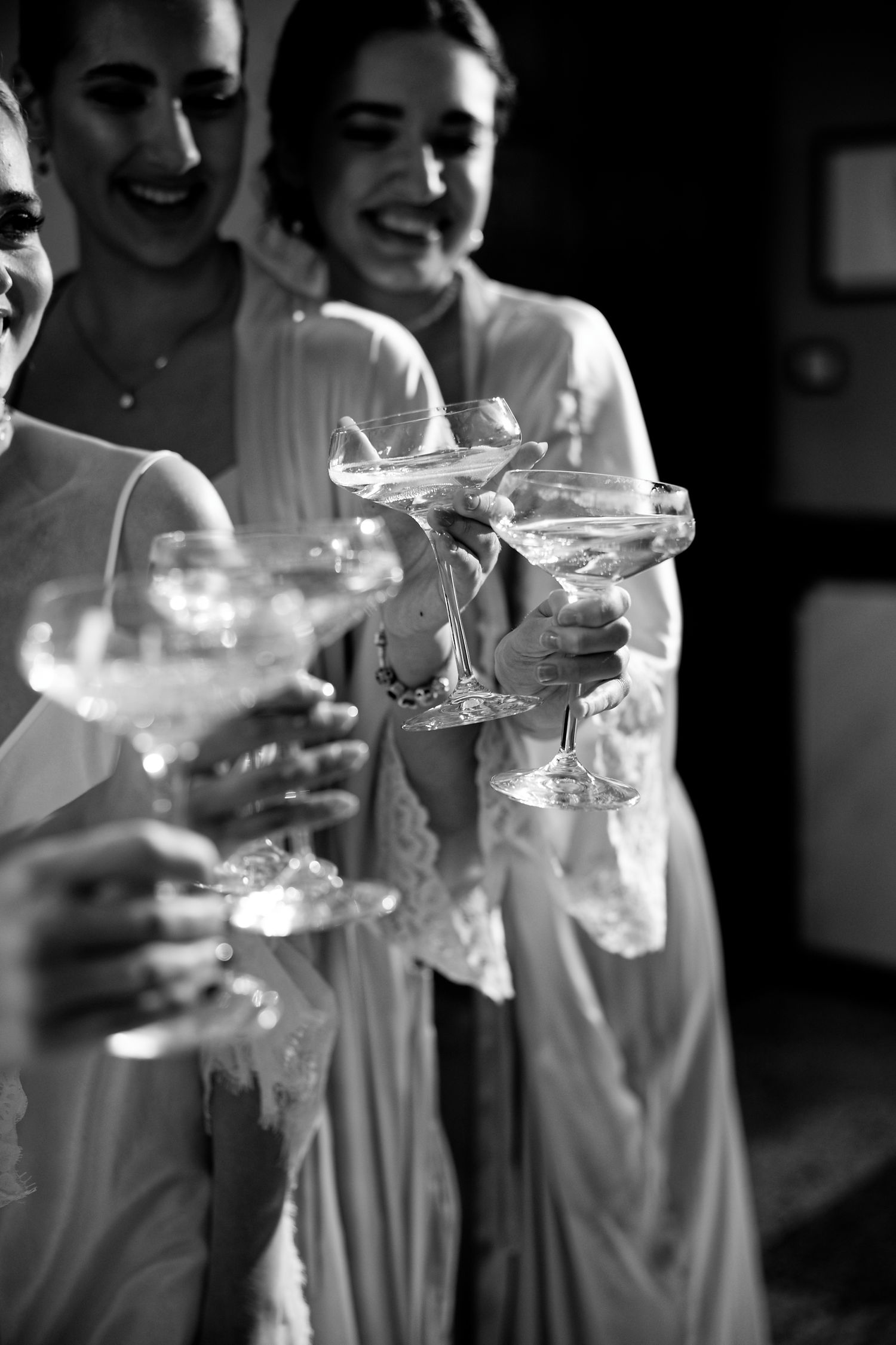 Black and white photo of bridesmaids toasting with champagne glasses in matching robes.