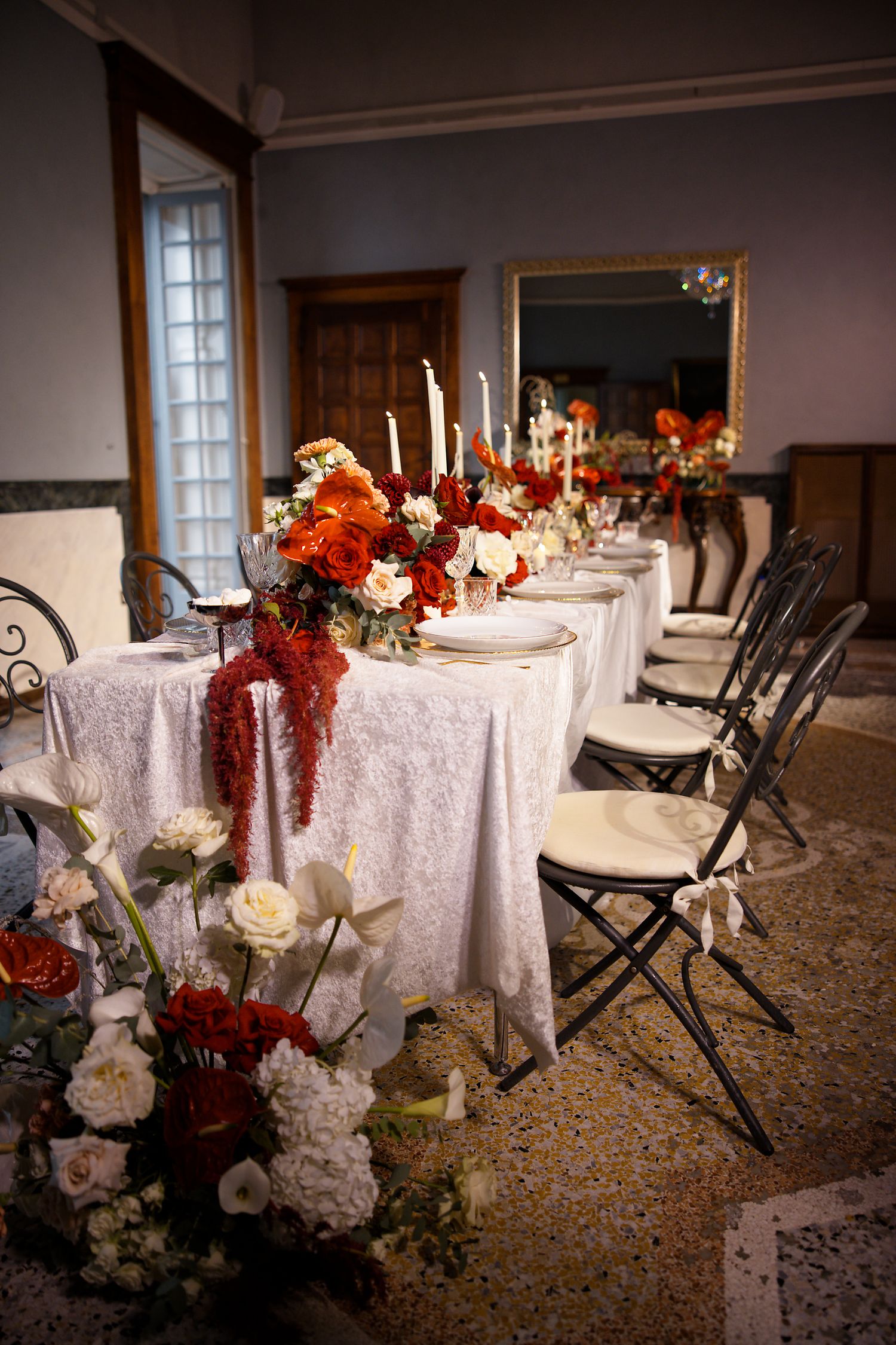 An elegant table setting with white linens, tall candles, and autumn-colored floral arrangements for a formal dinner party.