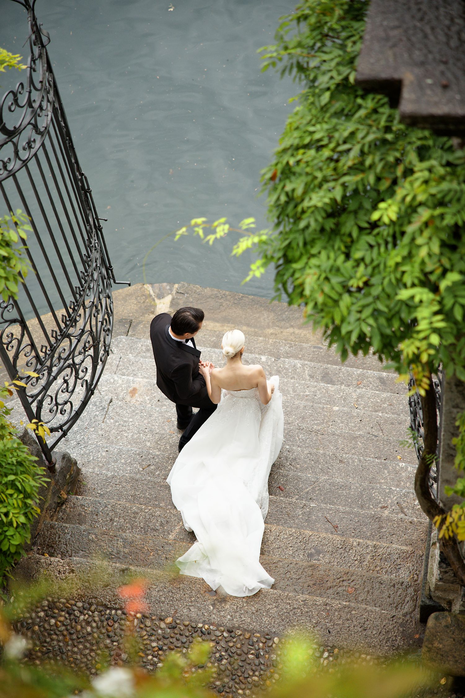Couple descending stone steps near an ornate wrought iron gate.