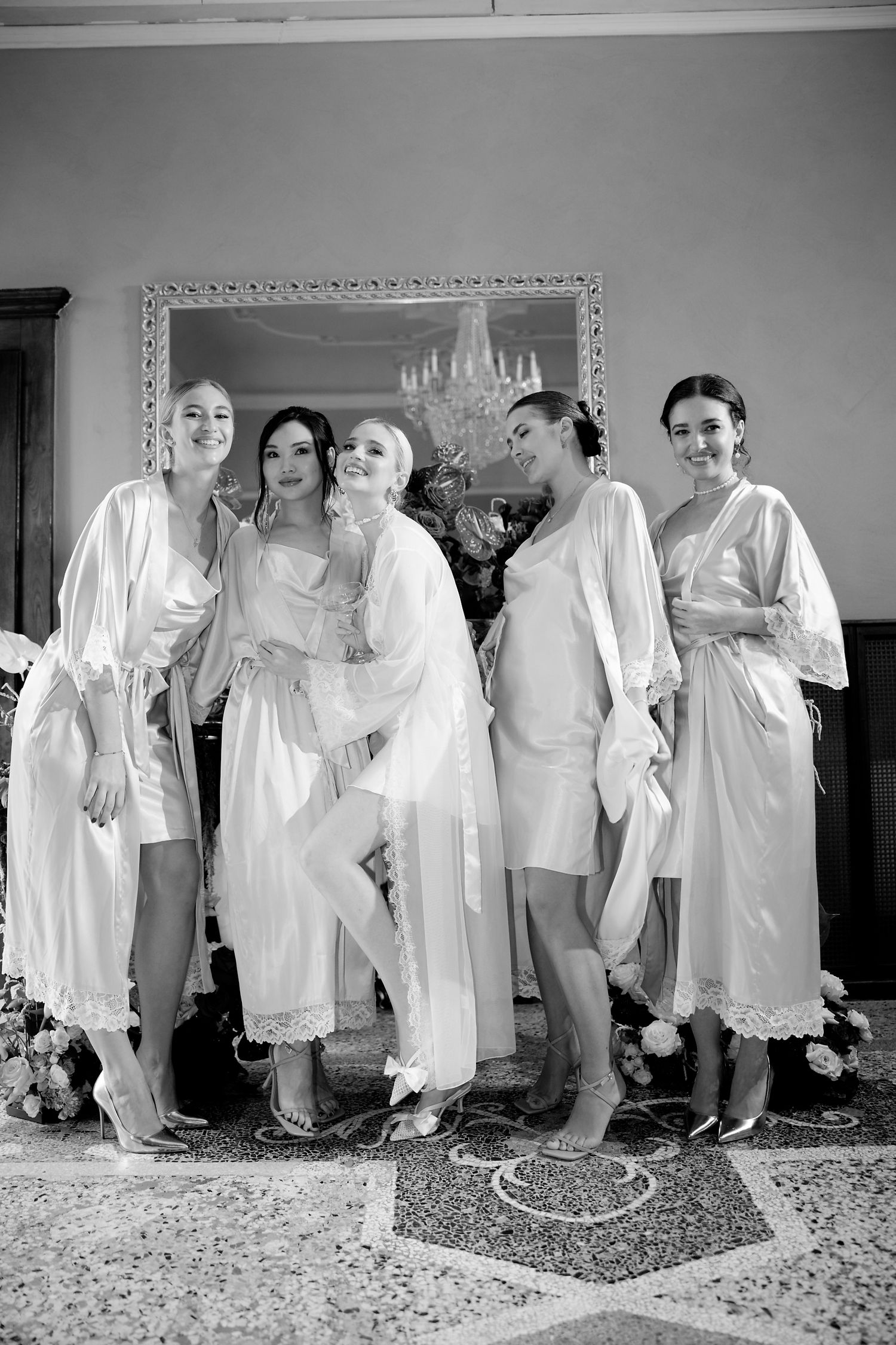 Black and white photo of wedding party in white robes posing together indoors.