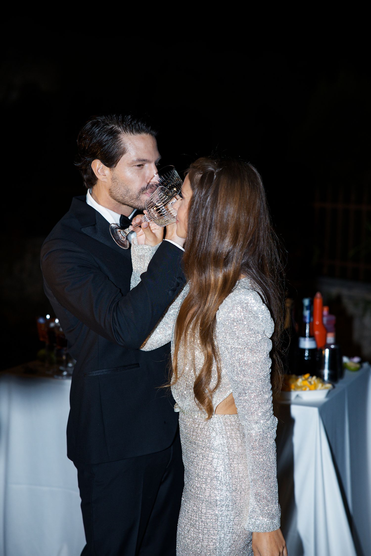 Couple sharing an intimate moment while drinking champagne at their wedding reception.