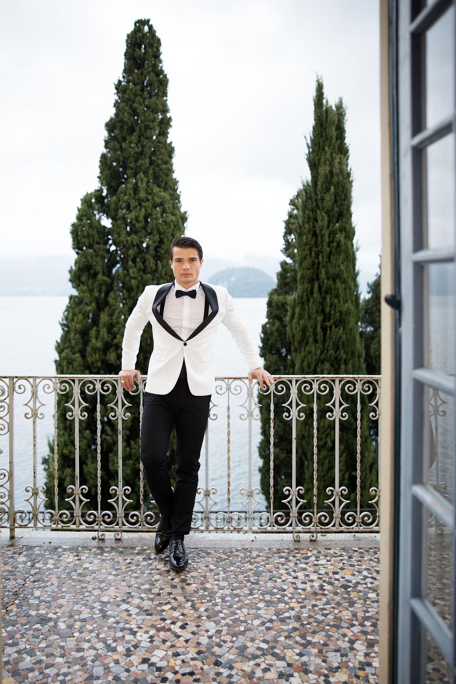 Wedding attire on balcony with Italian cypress trees and mountain vista backdrop.