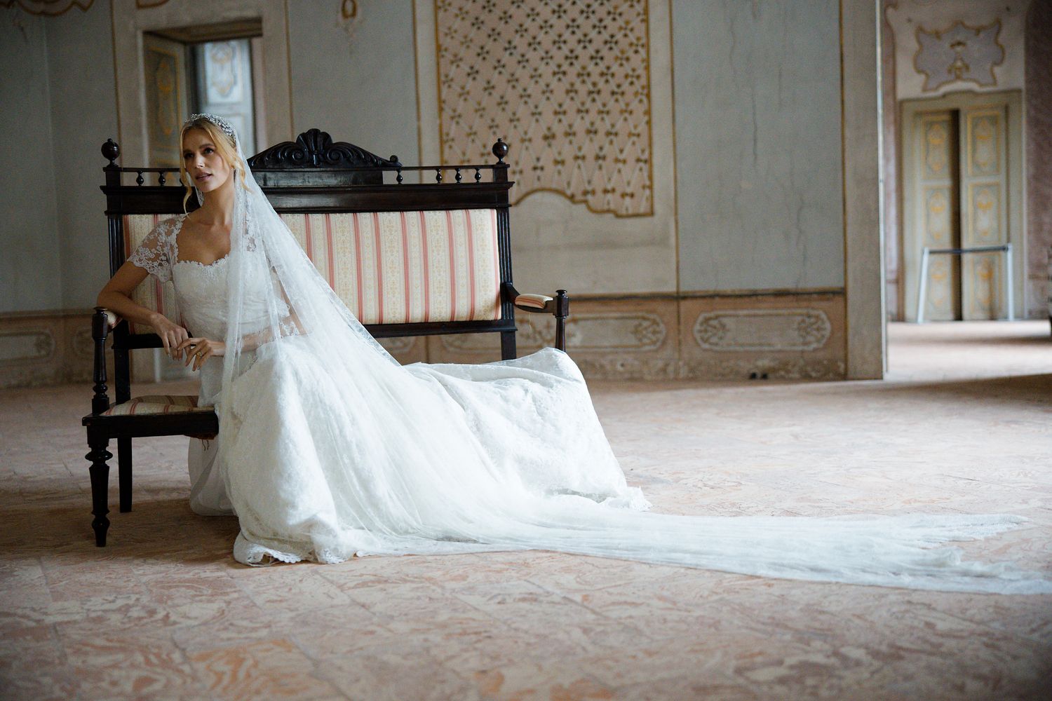 Wedding dress with long flowing train displayed in an elegant vintage room setting.