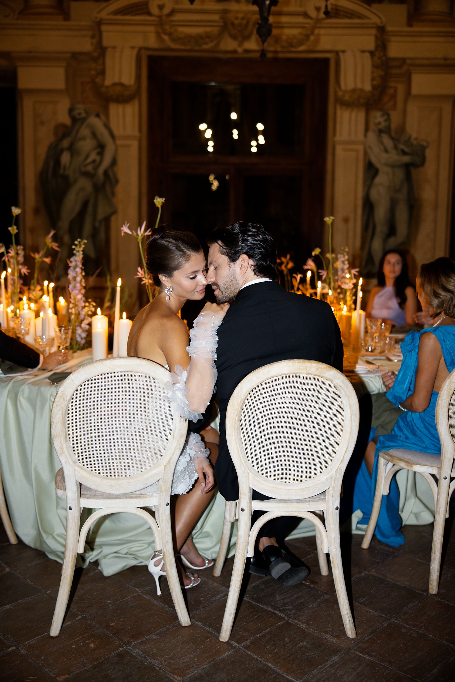An intimate moment captured at an elegant candlelit wedding reception dinner table.