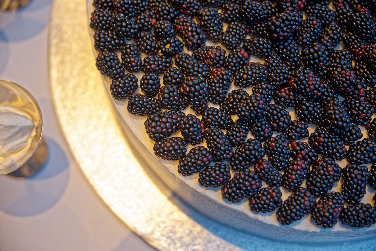 Close-up of an elegant wedding cake topped with fresh blackberries in a geometric pattern.