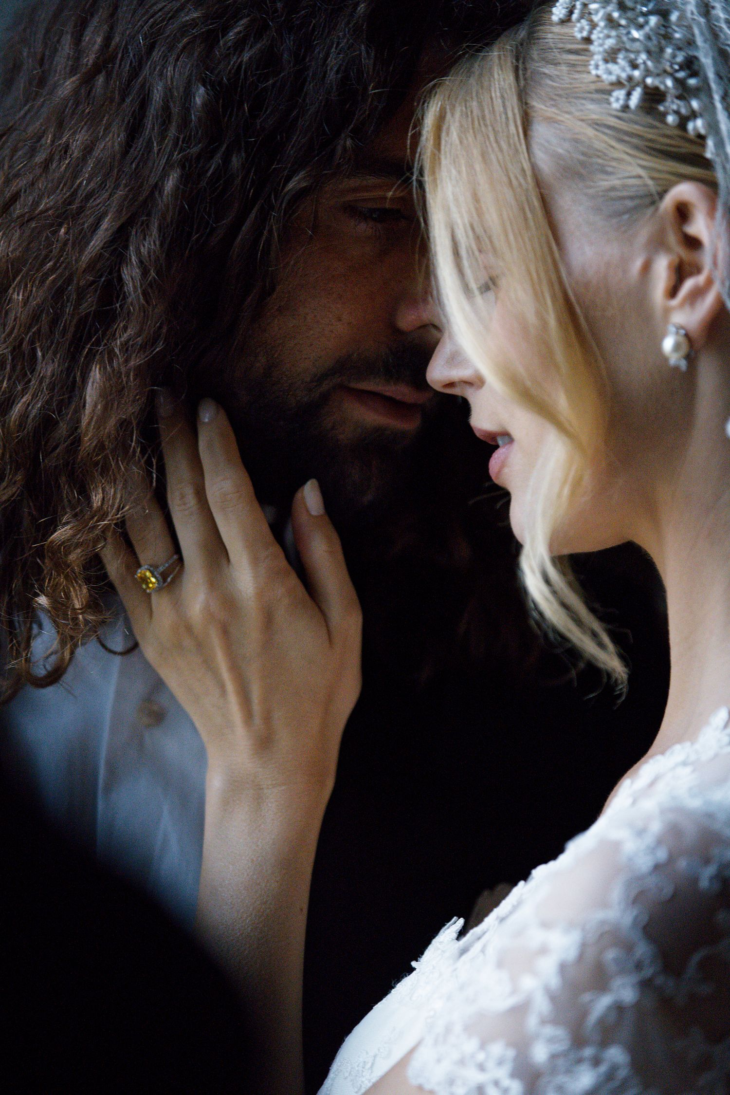 Intimate wedding portrait in soft lighting showing tender moment between couple with contrasting dark and light hair.