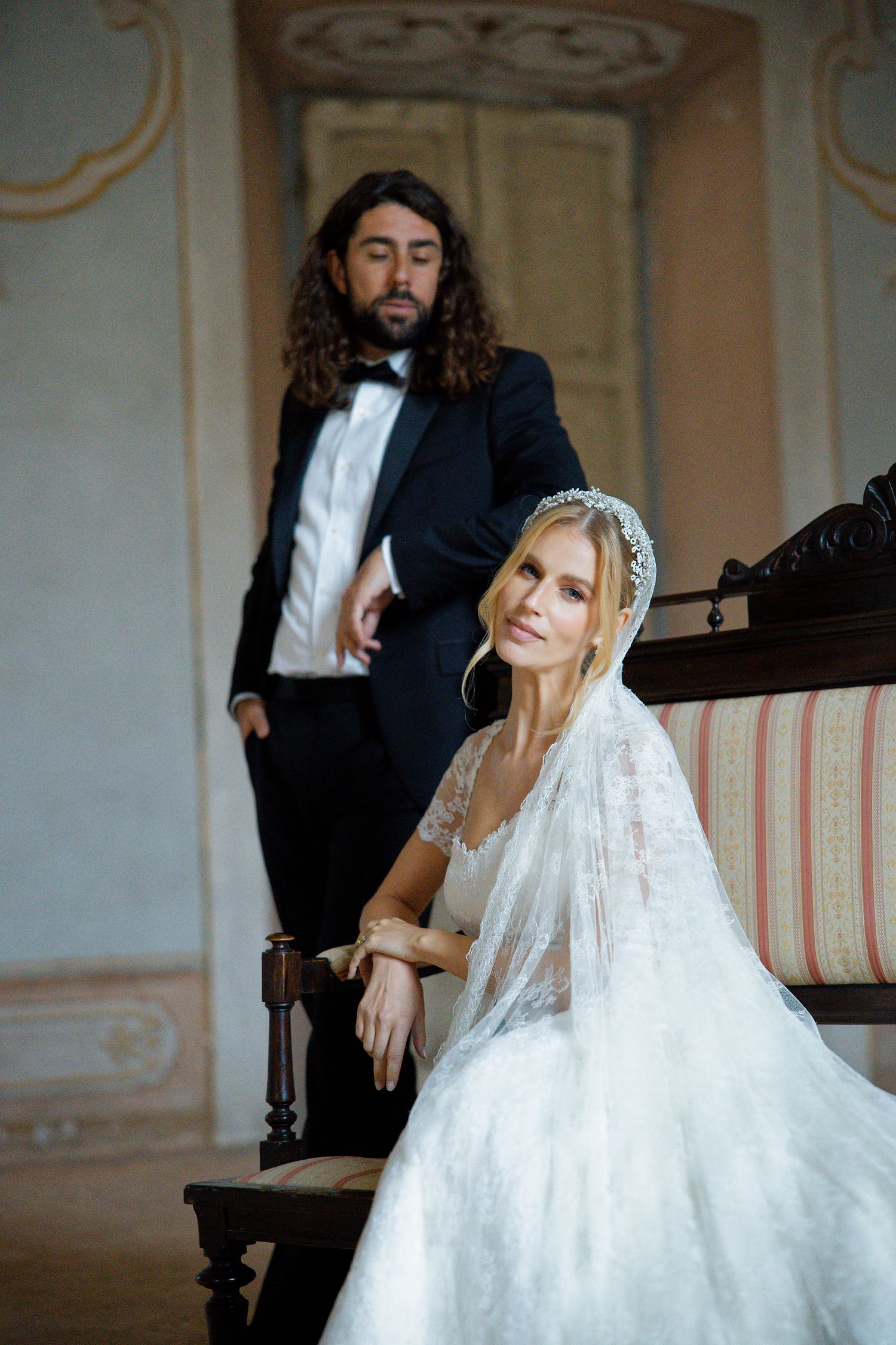 Wedding couple poses in vintage setting with ornate architectural details.