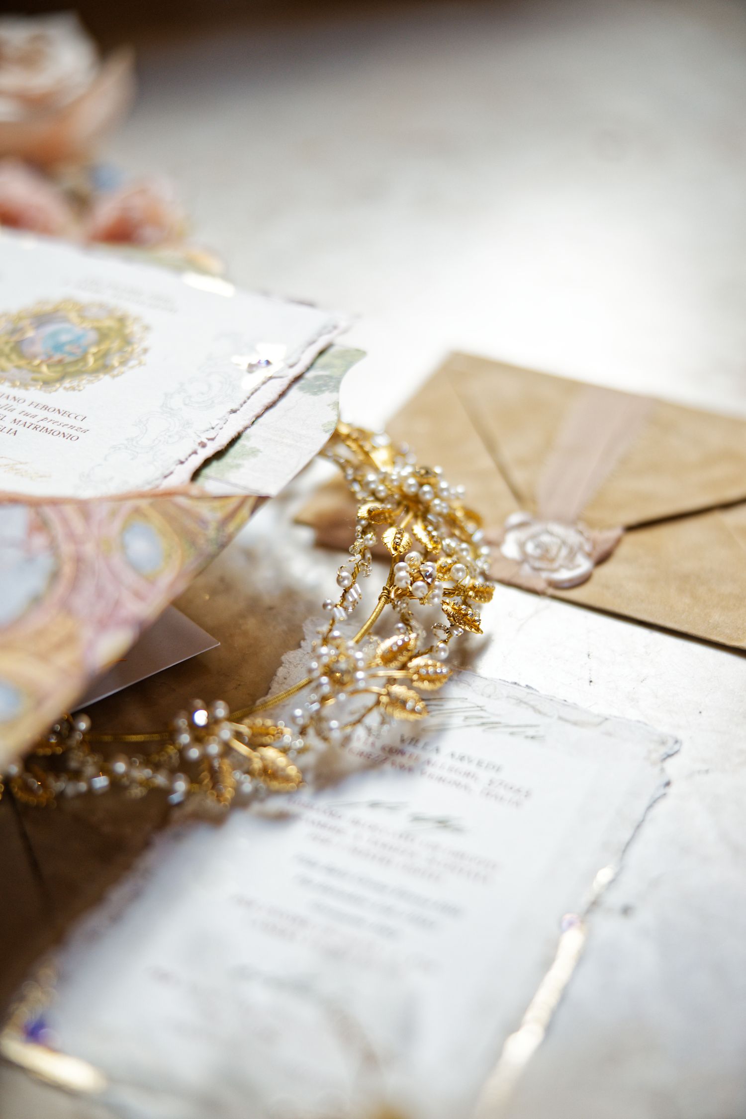 Elegant wedding stationery with gold accessories and delicate details laid out on a white surface.