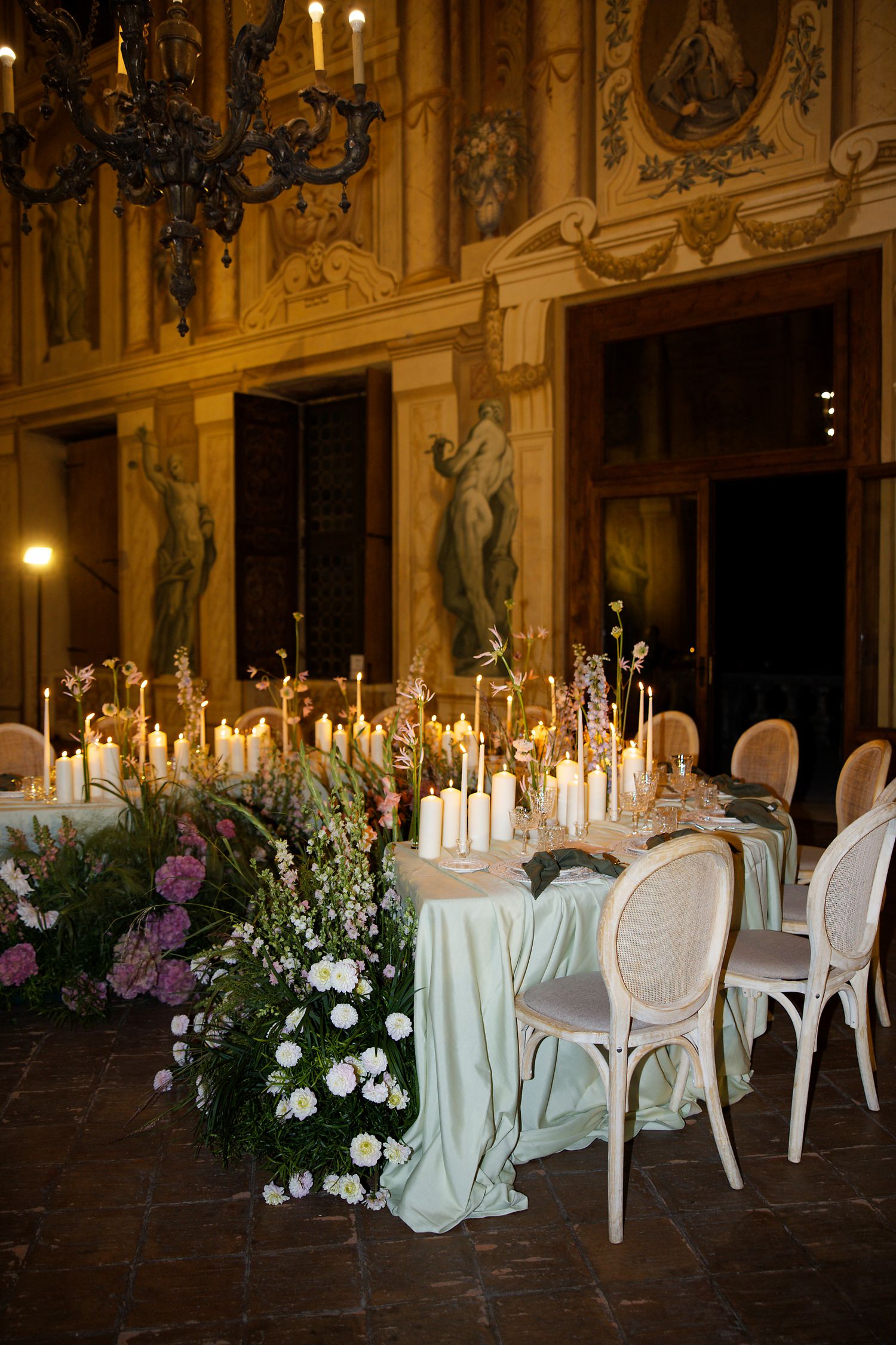 Elegant wedding table setting with candles and floral arrangements in ornate gold room.