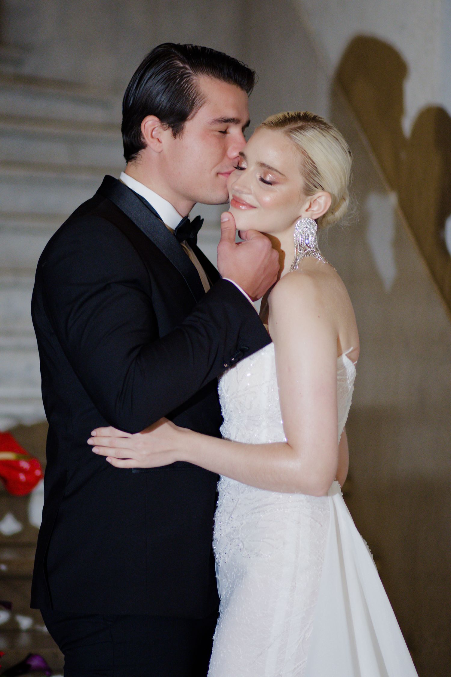 Intimate moment between wedding couple on stairs with romantic lighting and floral decor.