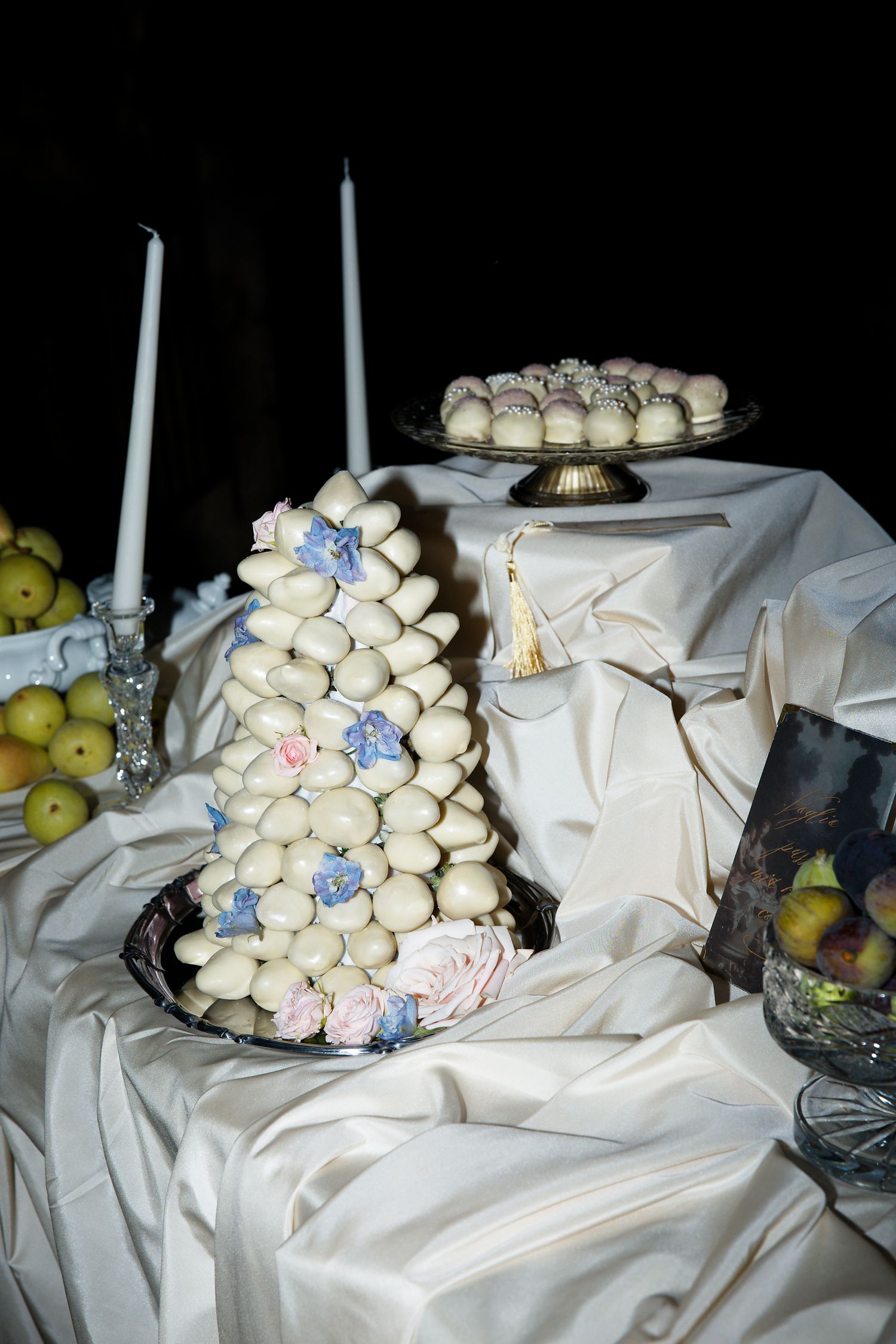 Wedding dessert table with white macaron tower, candles and draped fabric.