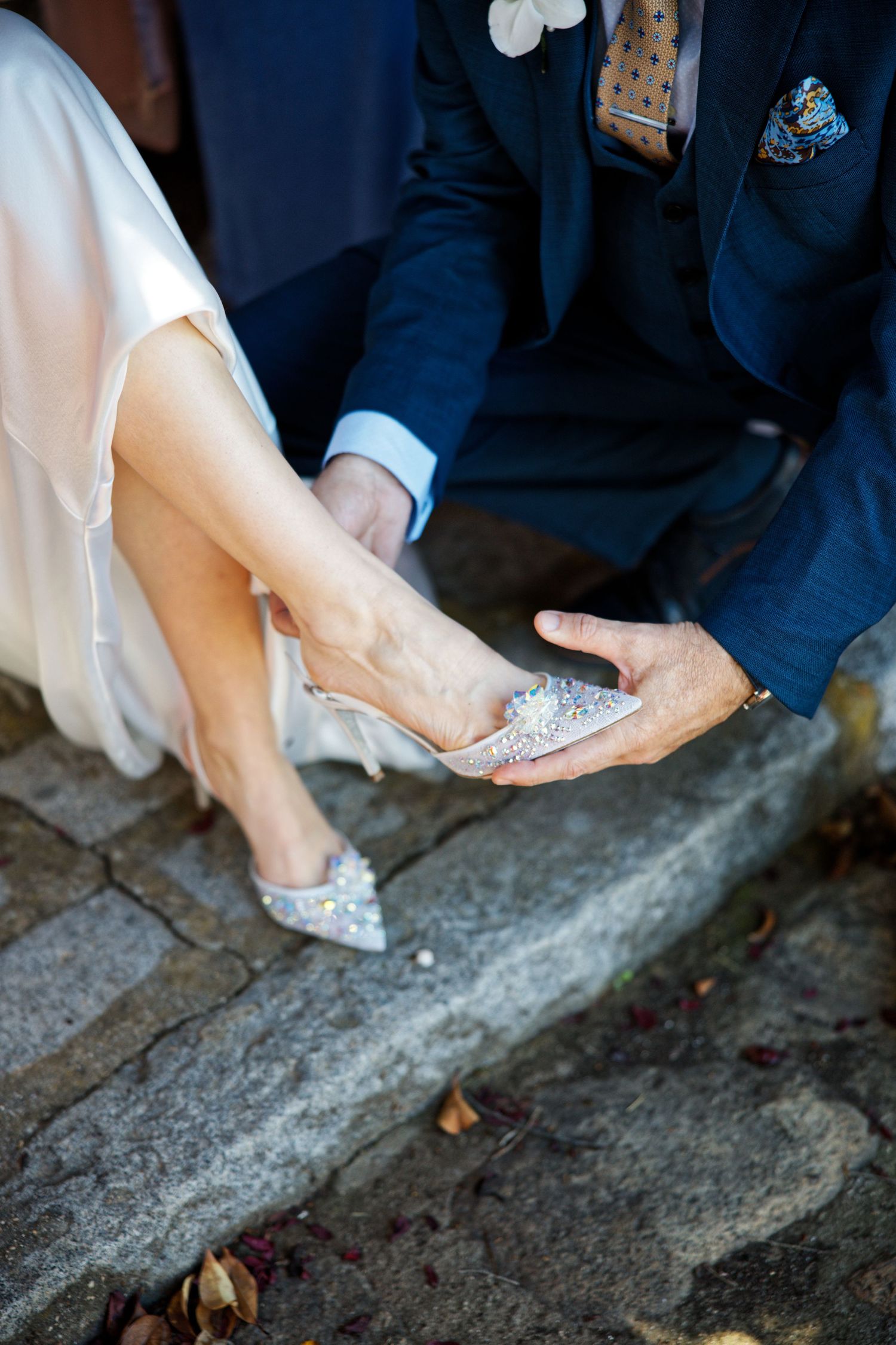 Close-up shots of bridal shoes being fitted on stone steps during a wedding ceremony.