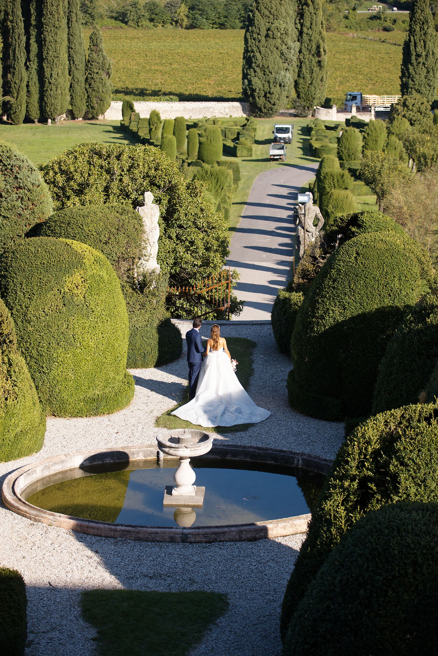 Aerial view of formal gardens with symmetrical hedges, fountain and walking path.