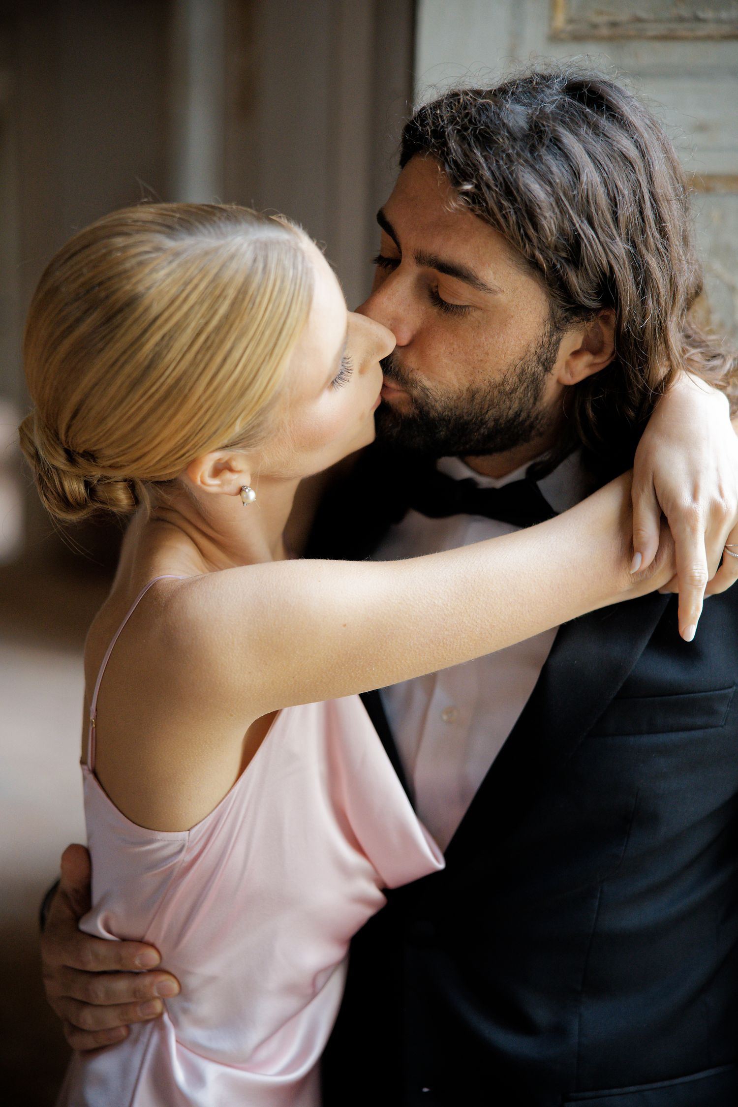 A romantic wedding couple sharing an intimate kiss in formal attire.