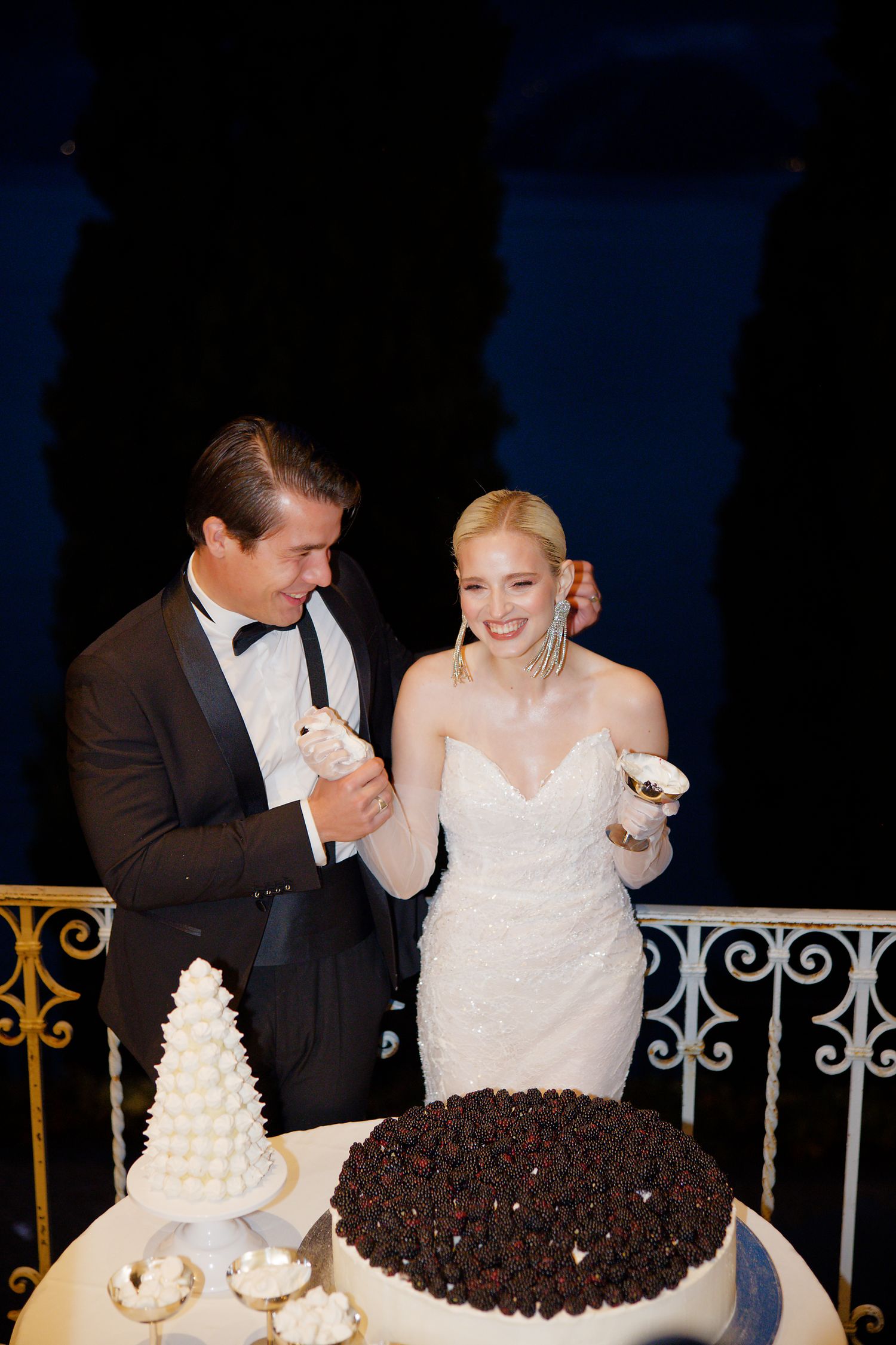A bride and groom cutting their wedding cake featuring one white tiered cake and one chocolate cake.