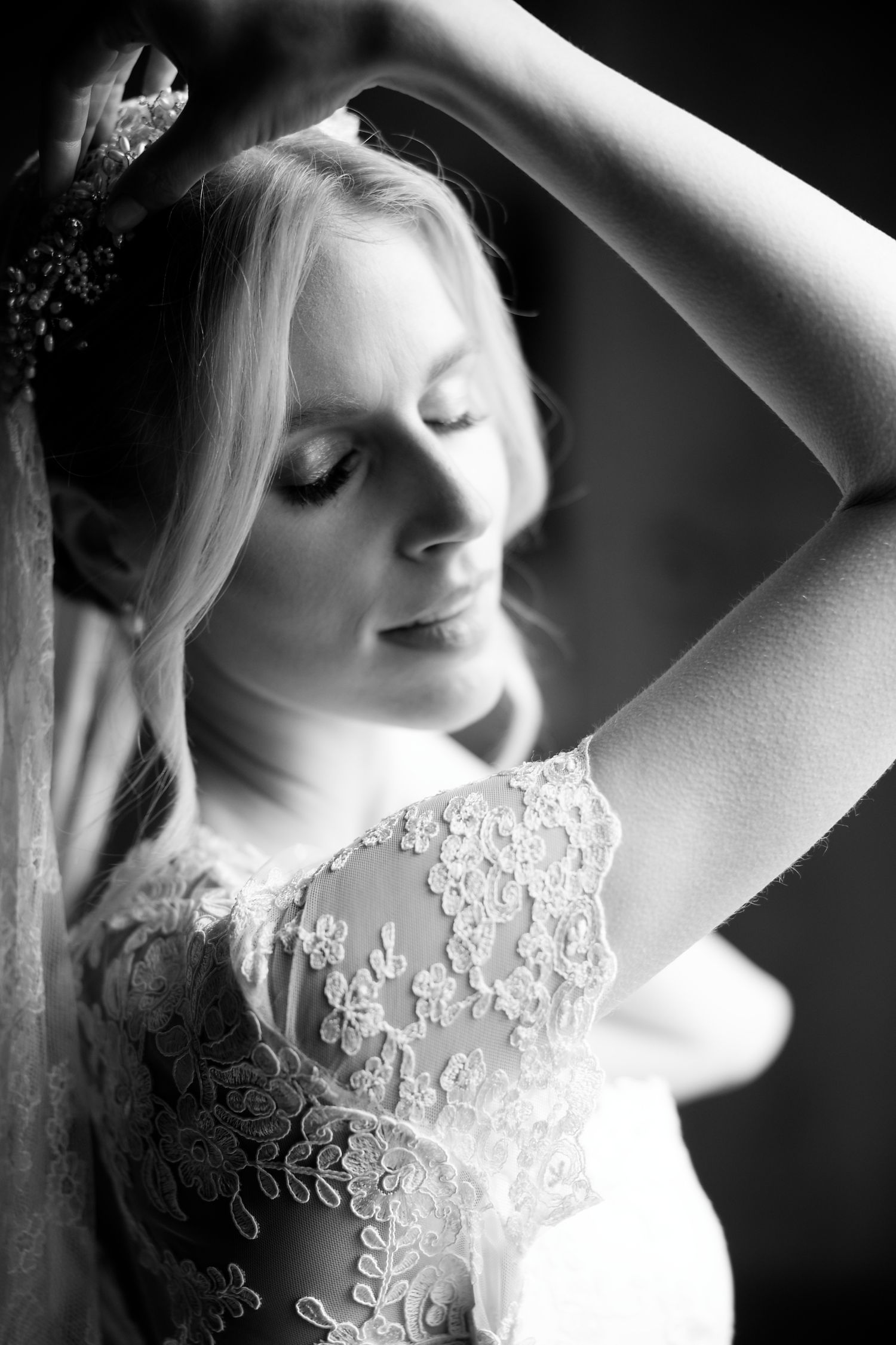 Artistic black and white portrait of a bride in lace dress and veil.