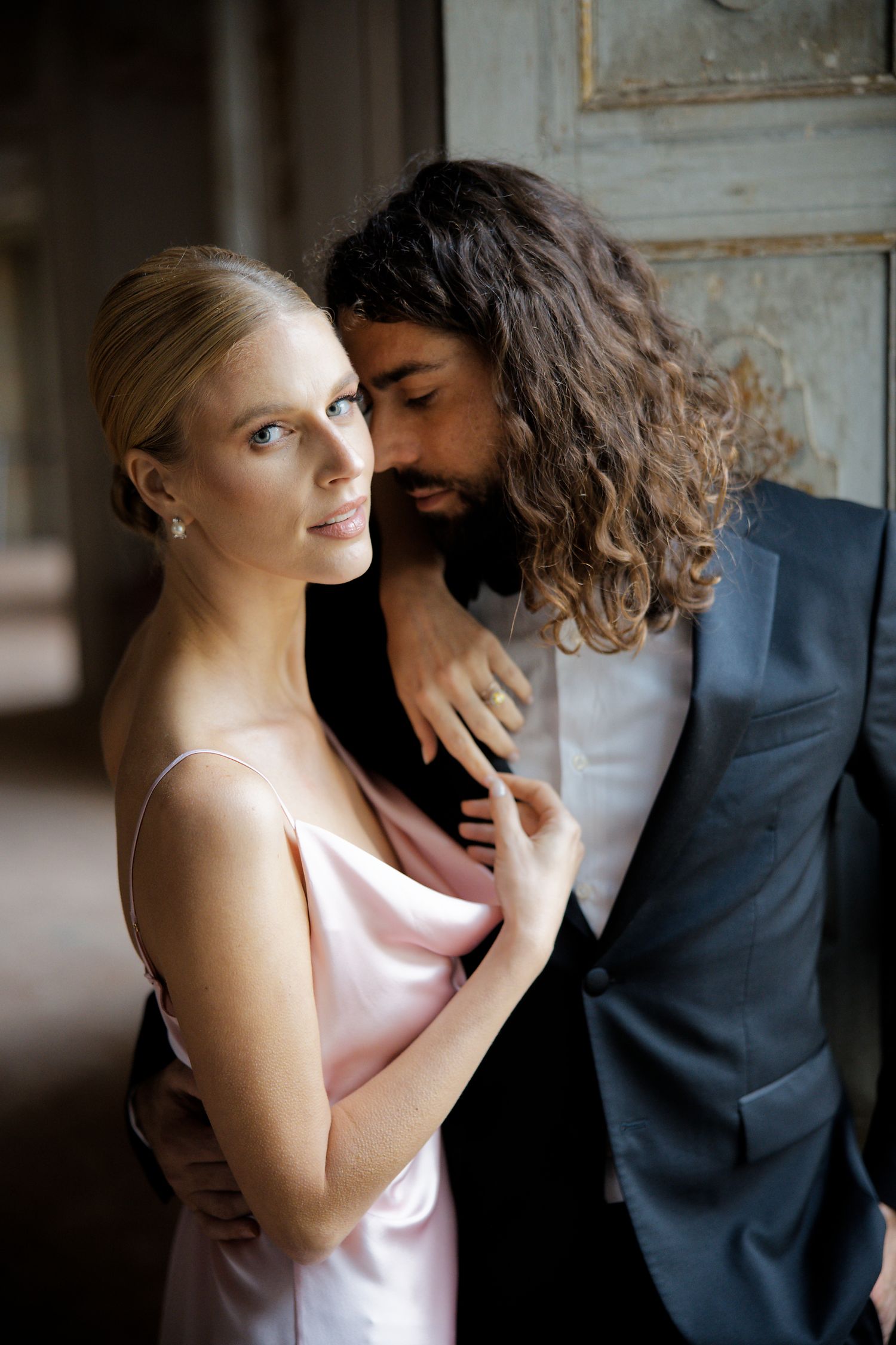 Intimate couple portrait with contrasting light and dark attire in vintage setting.