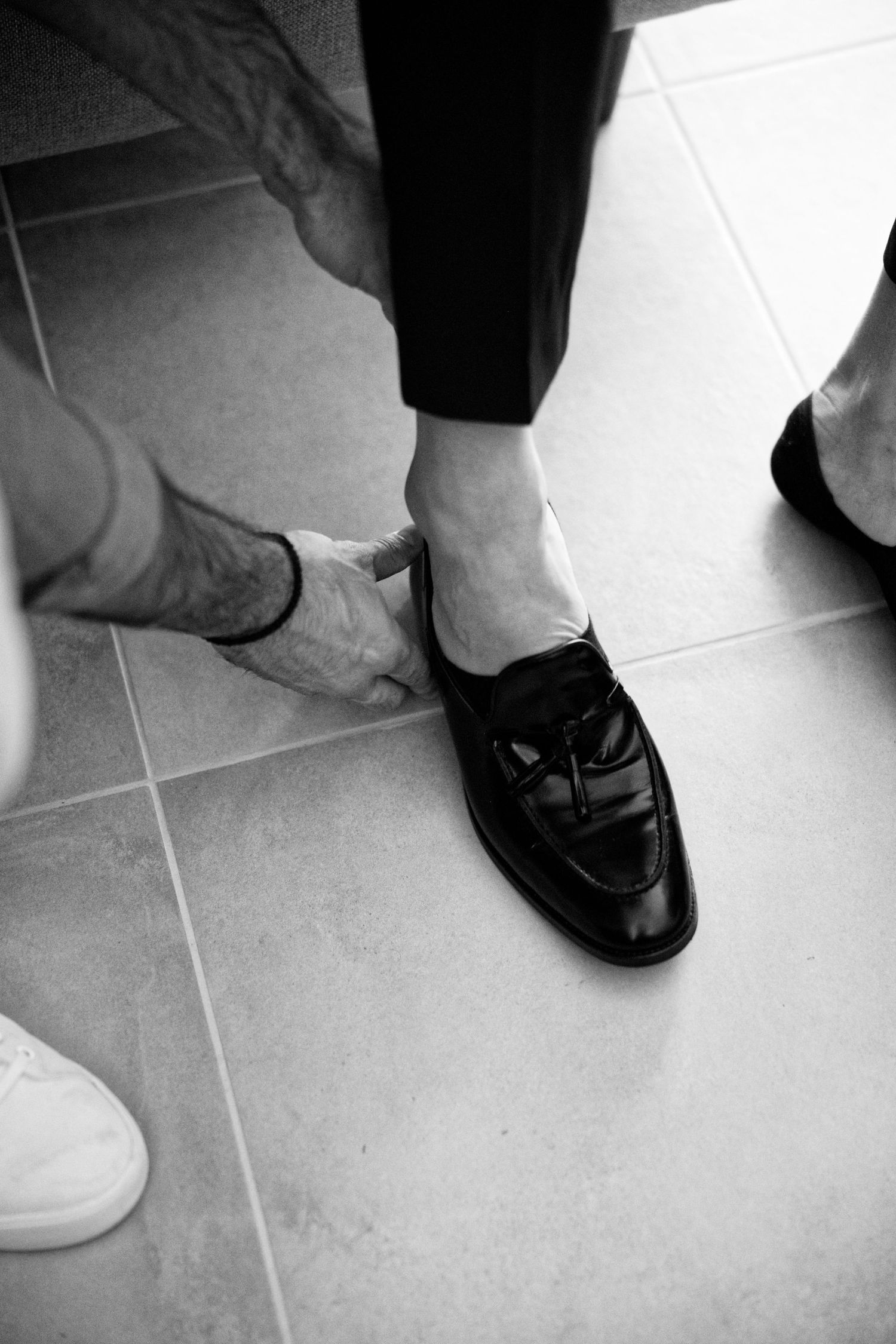 A sequence of black and white images showing formal dress shoes on a tiled floor.