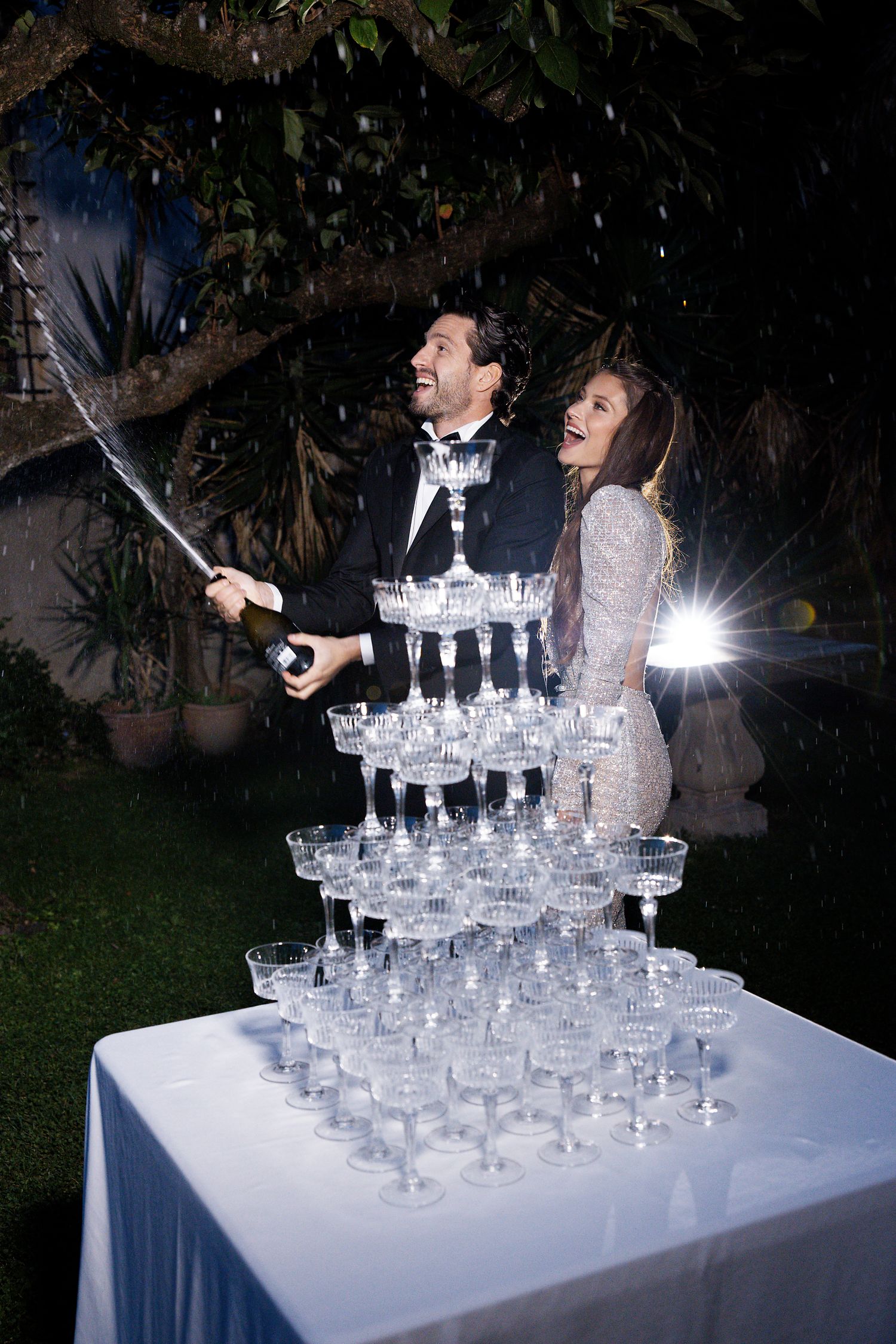 A celebratory moment with champagne being poured over a tower of glasses at an evening reception.
