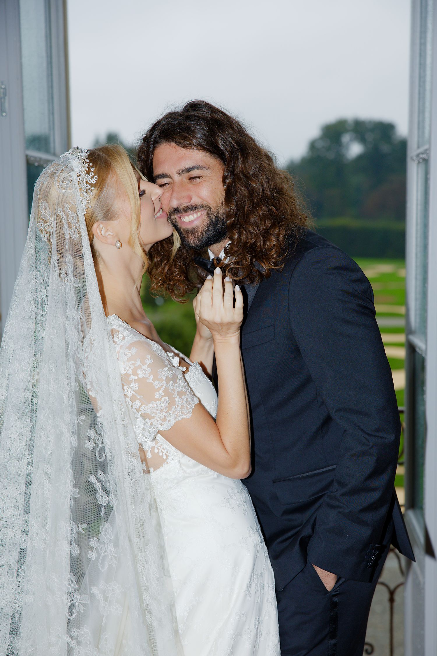 An intimate wedding moment between a couple sharing a tender embrace by a window.