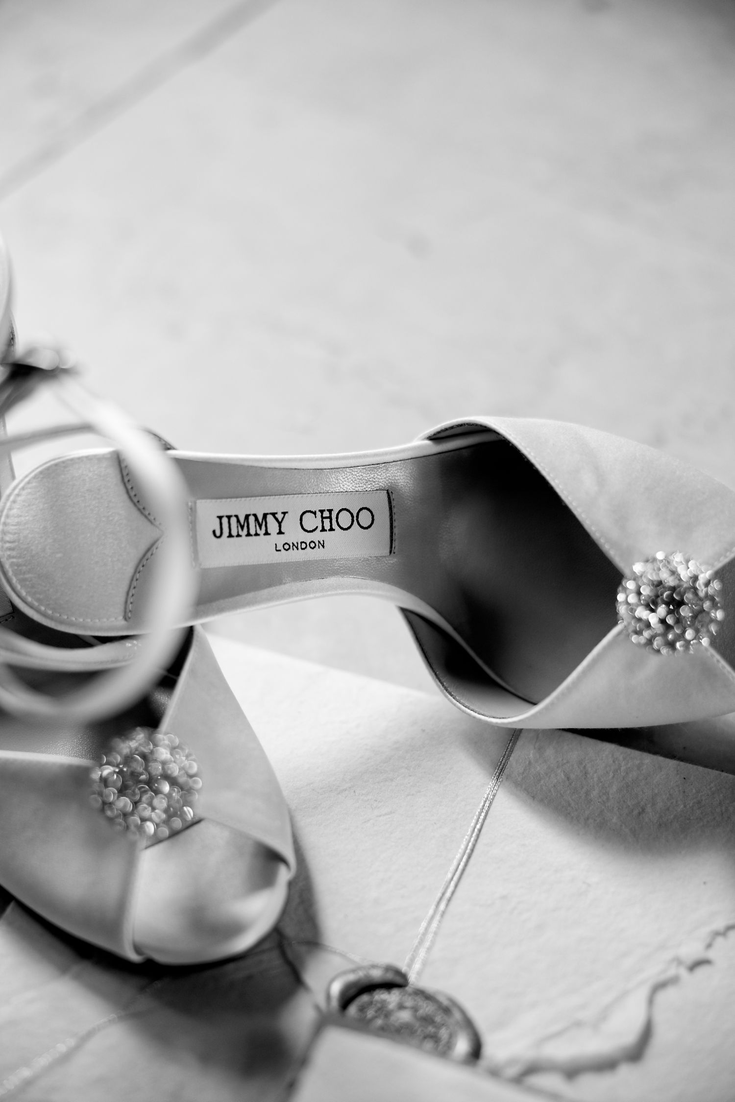 Close-up of elegant white satin Jimmy Choo bridal shoe with crystal detail.