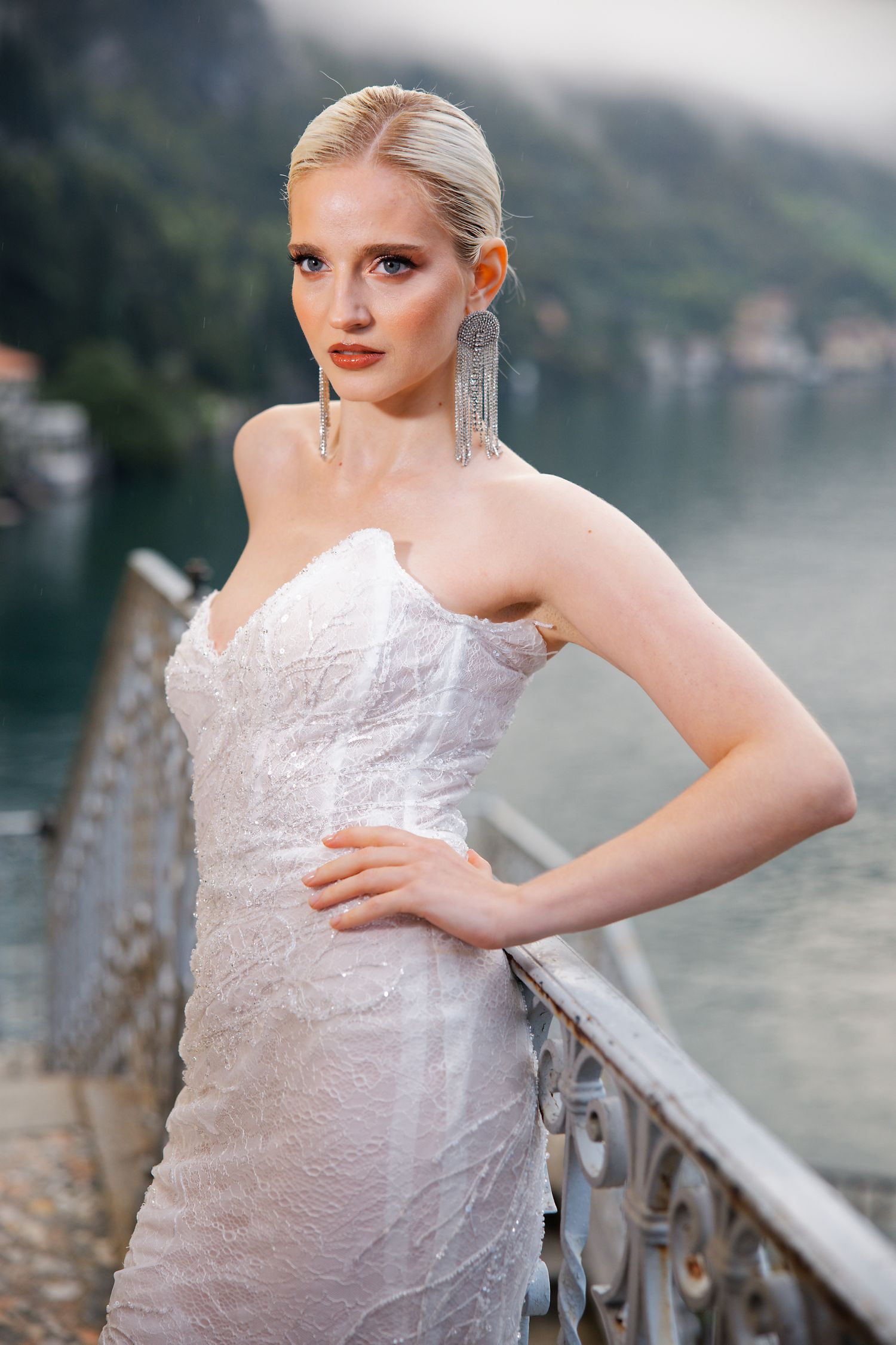 A stunning bridal portrait on a lakeside balcony with mountains in the background.