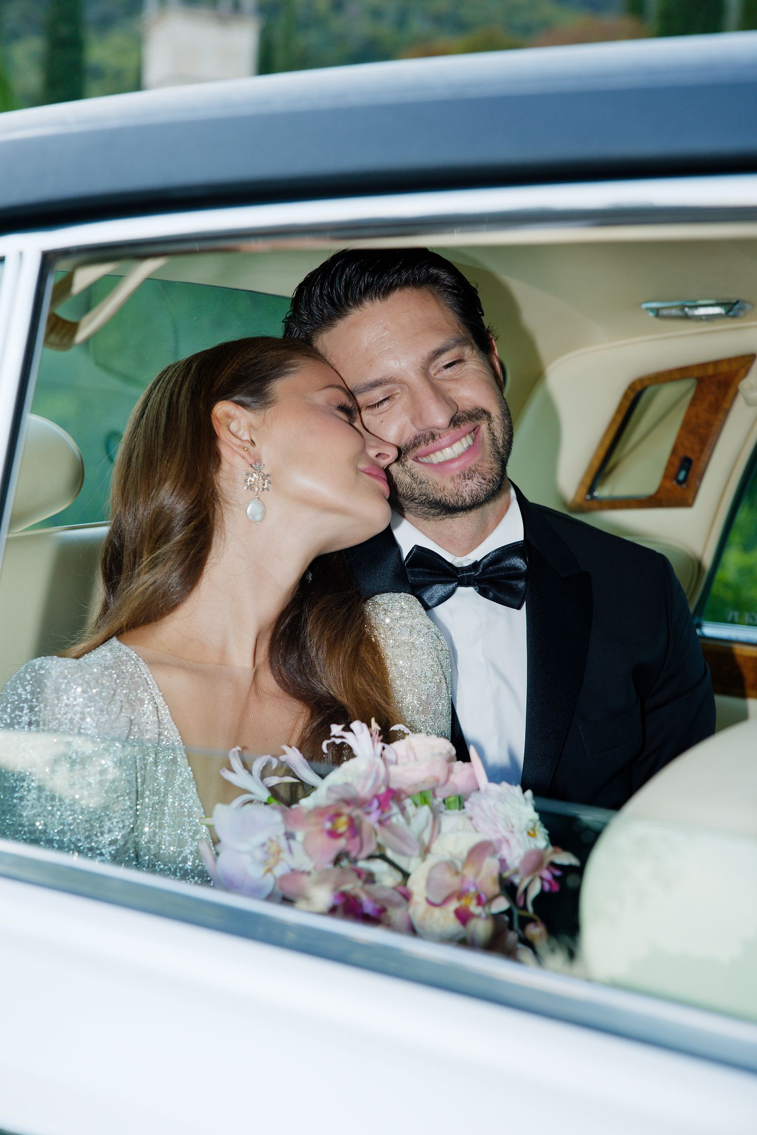 Romantic wedding couple shares an intimate moment in vintage car backseat.
