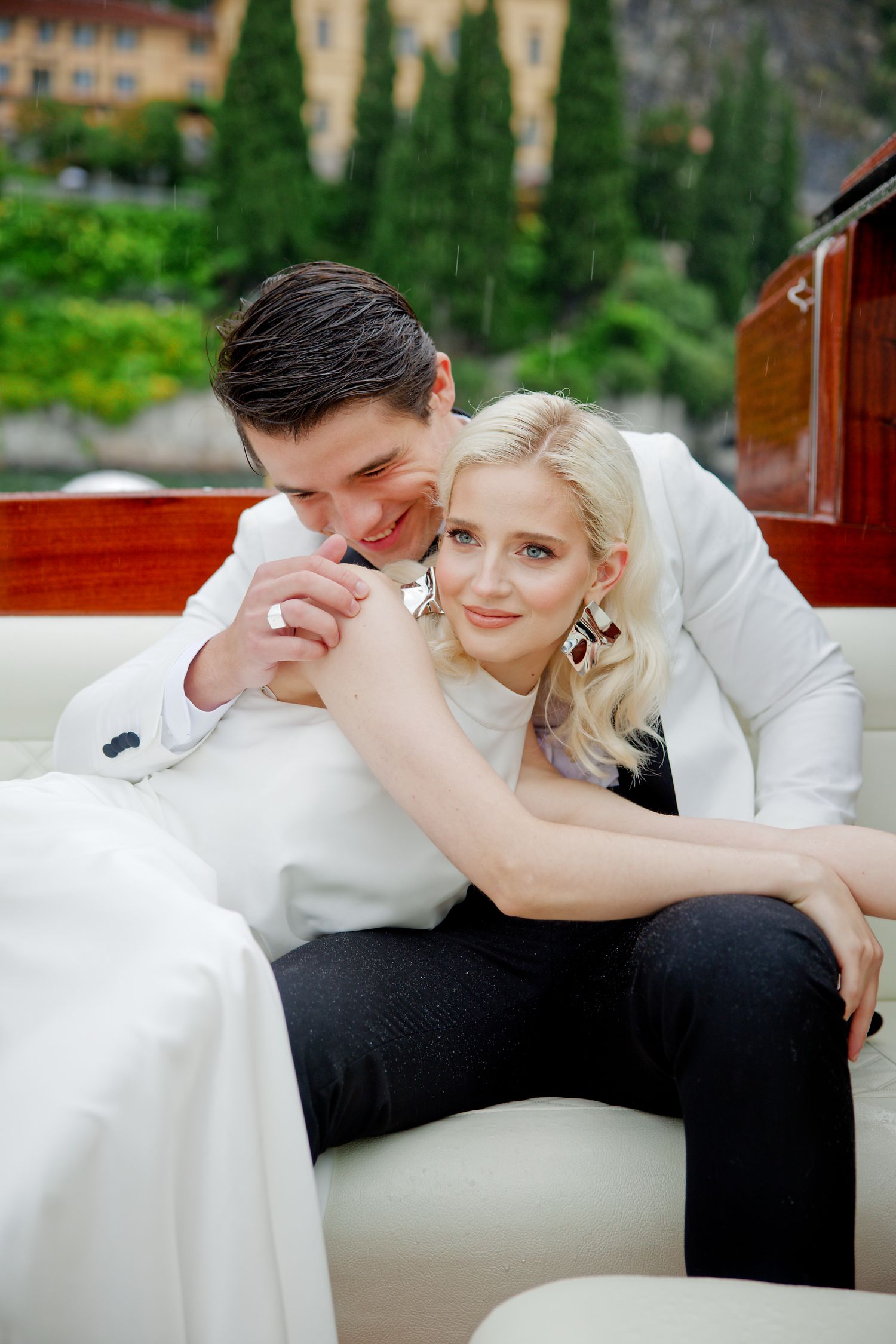 Romantic wedding couple sharing intimate moment on luxury boat with scenic Italian lake backdrop.