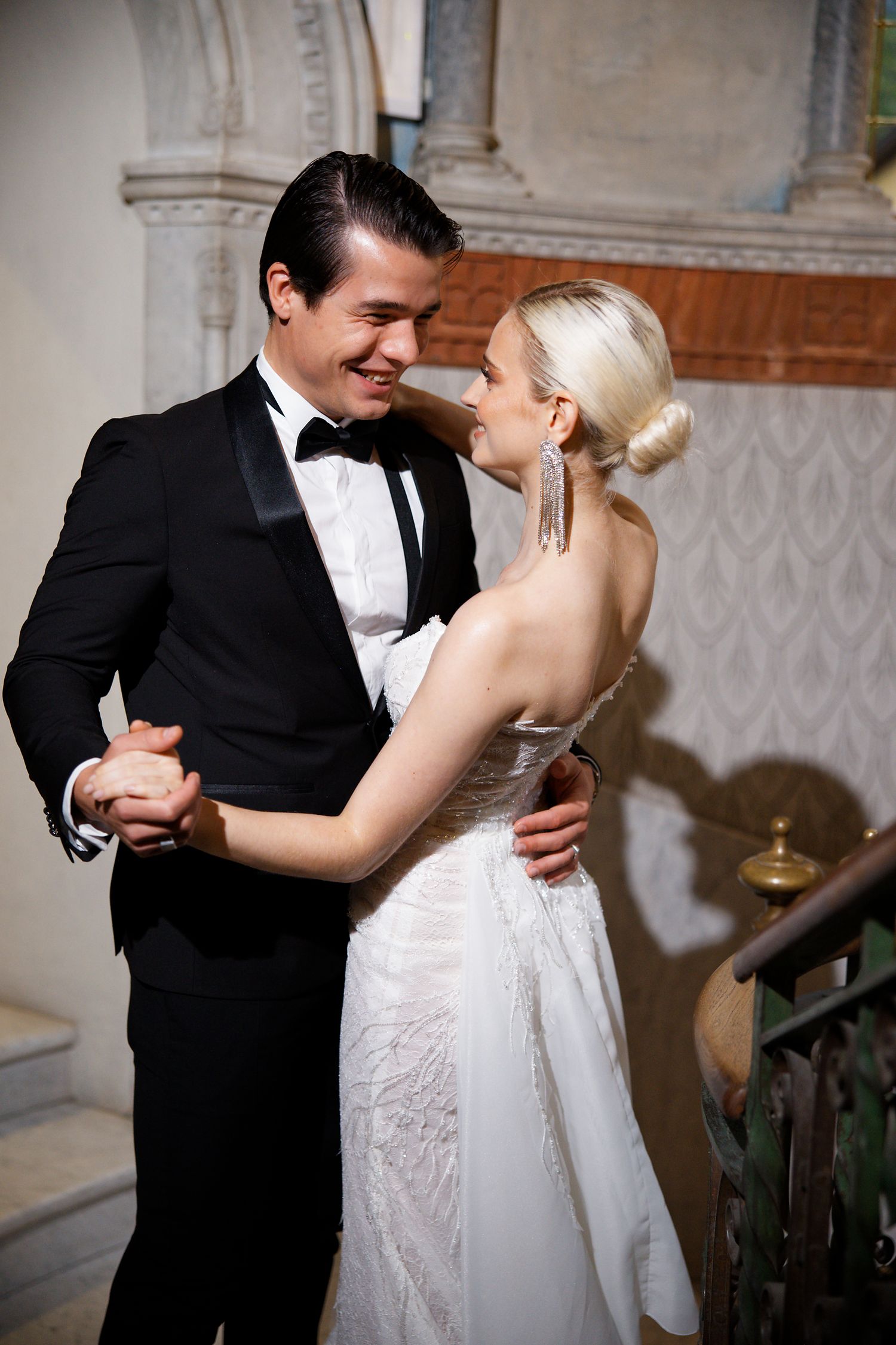 Elegant couple dancing in formal attire at an indoor wedding reception.