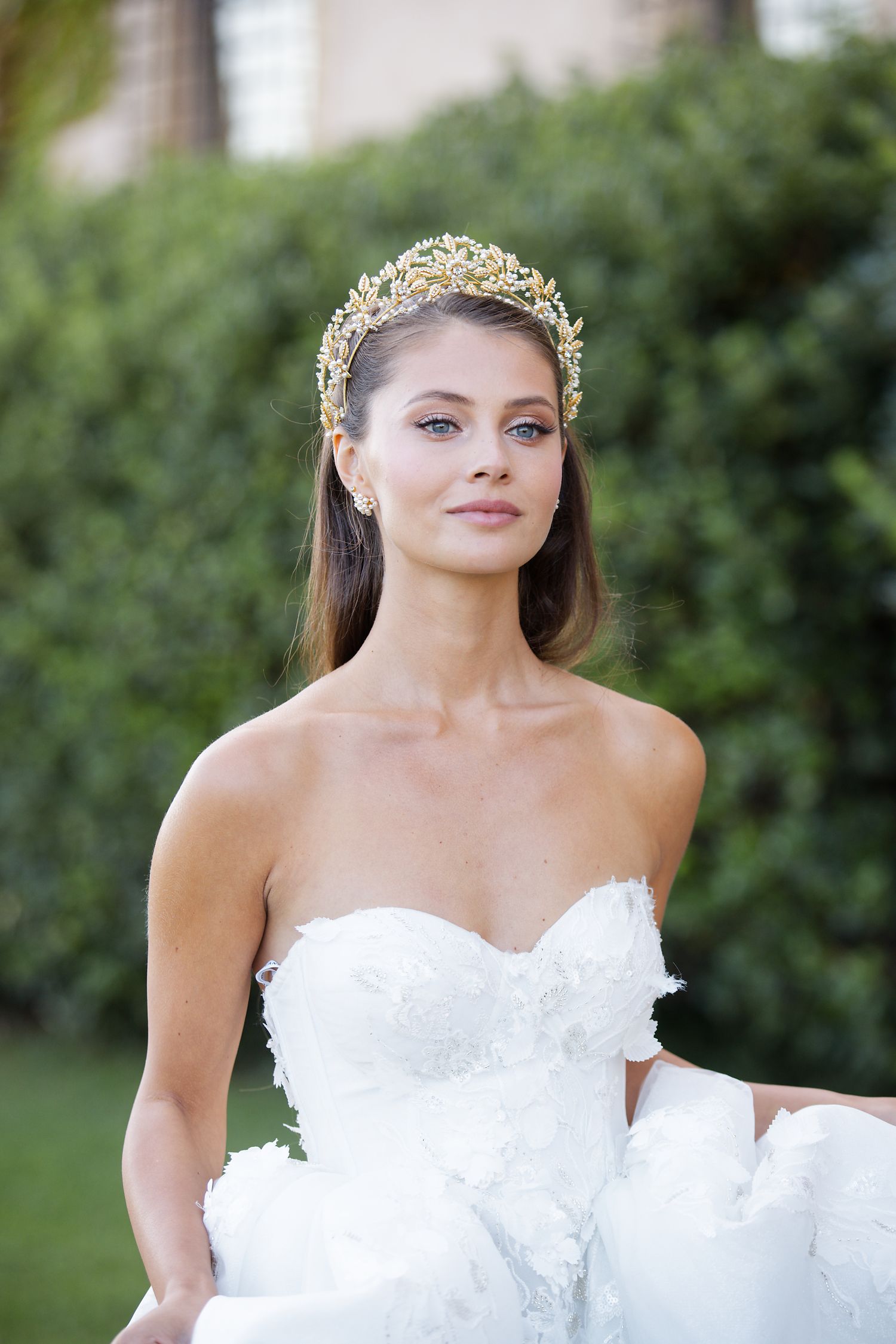 Elegant bridal portrait featuring ornate golden crown and sweetheart neckline gown in garden setting.