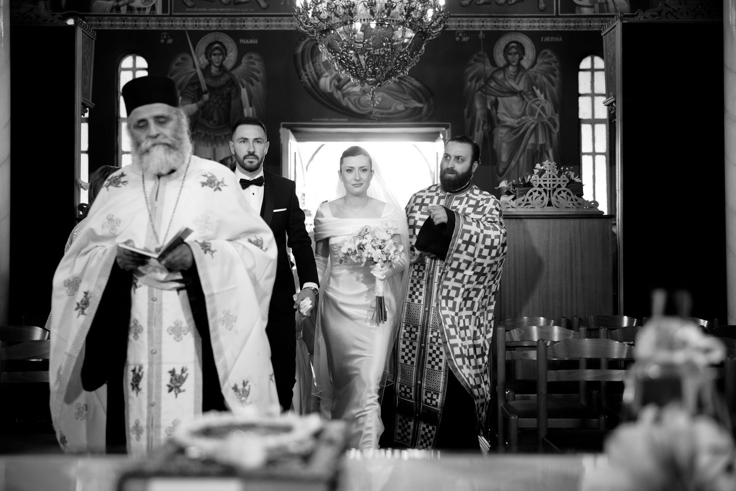 Black and white photo of an Orthodox wedding ceremony inside a traditional church with religious icons.