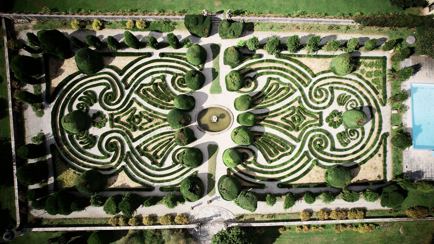 Aerial view of an ornate formal garden with symmetrical spiral patterns and pathways viewed from above.