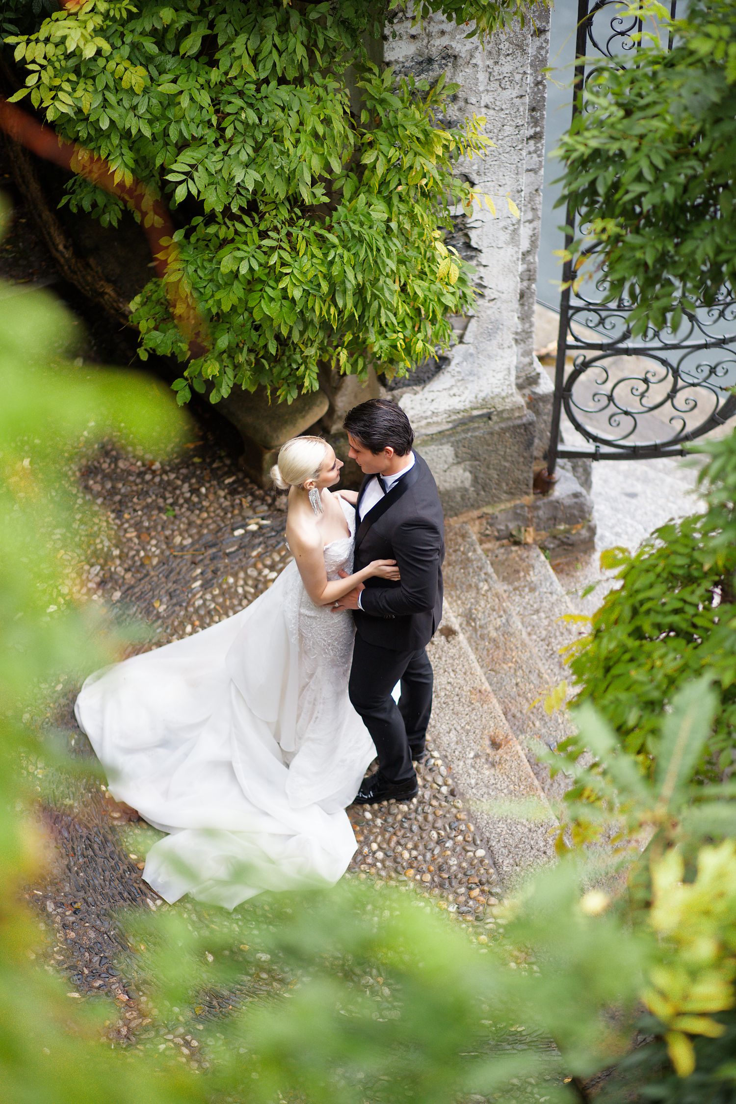 An aerial view of a romantic wedding moment amid lush greenery and ornate stone architecture.