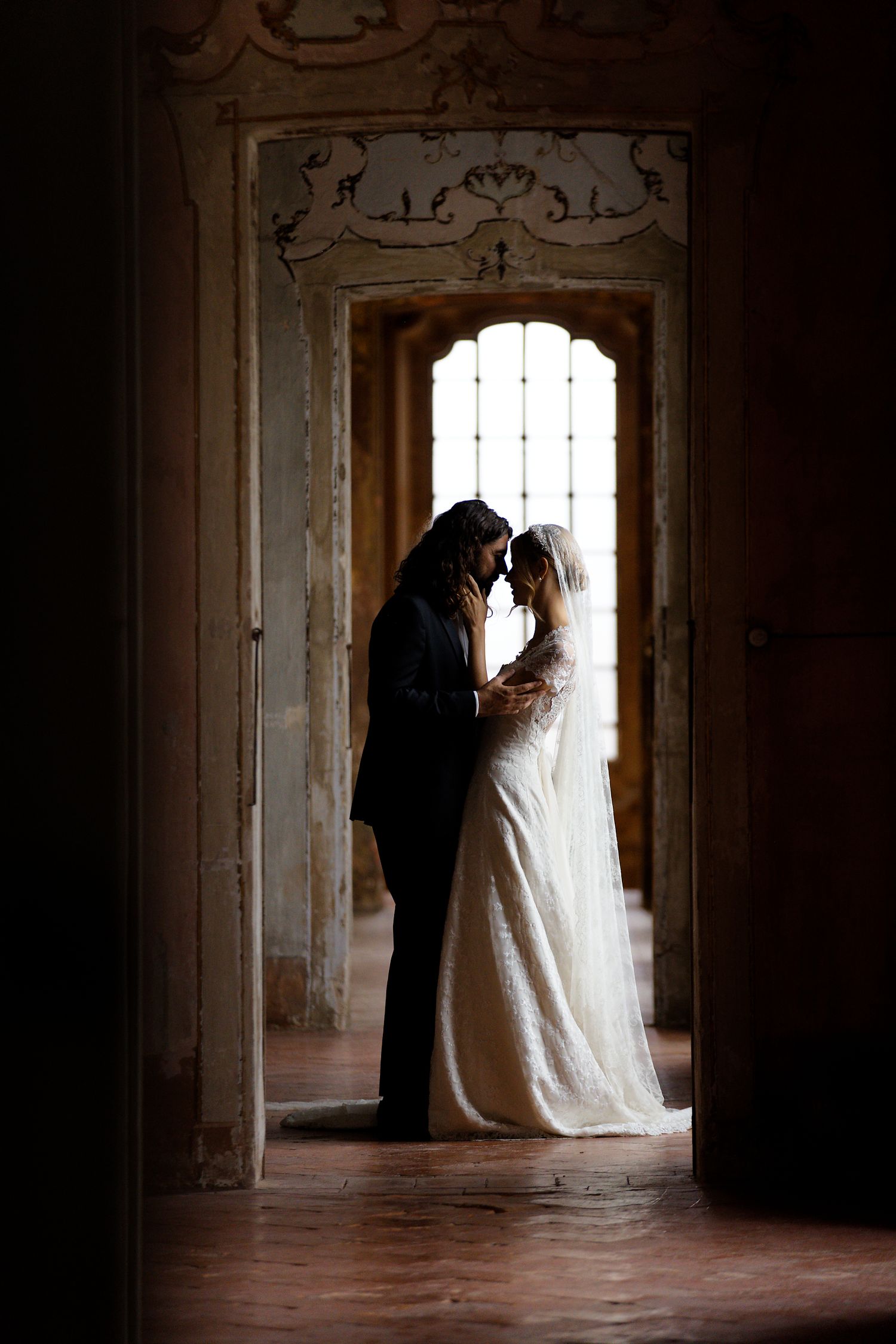 Silhouette of newlyweds standing in ornate doorway creates romantic ambiance.