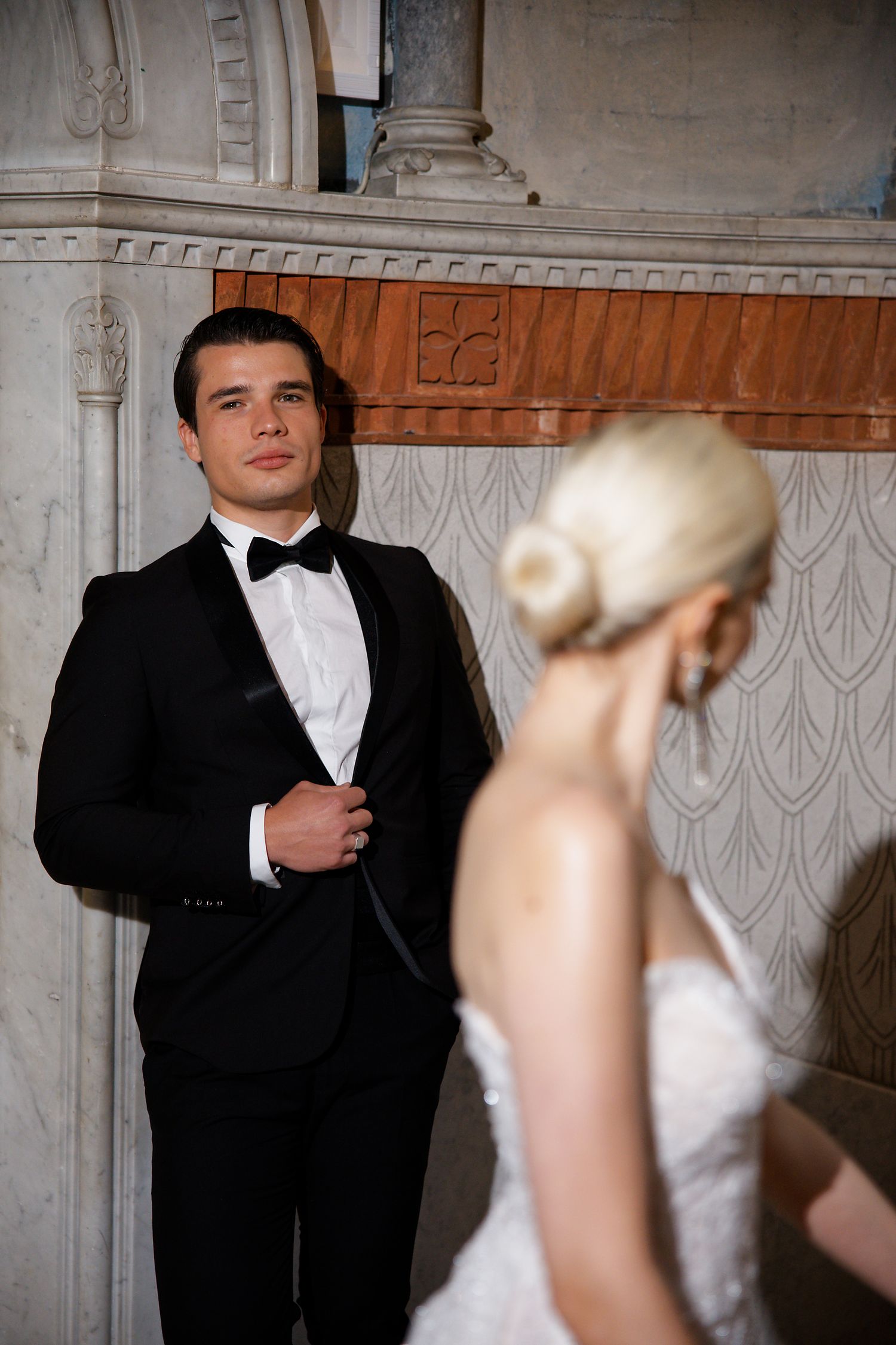 An elegant wedding portrait in a classic architectural setting with ornate wall details.