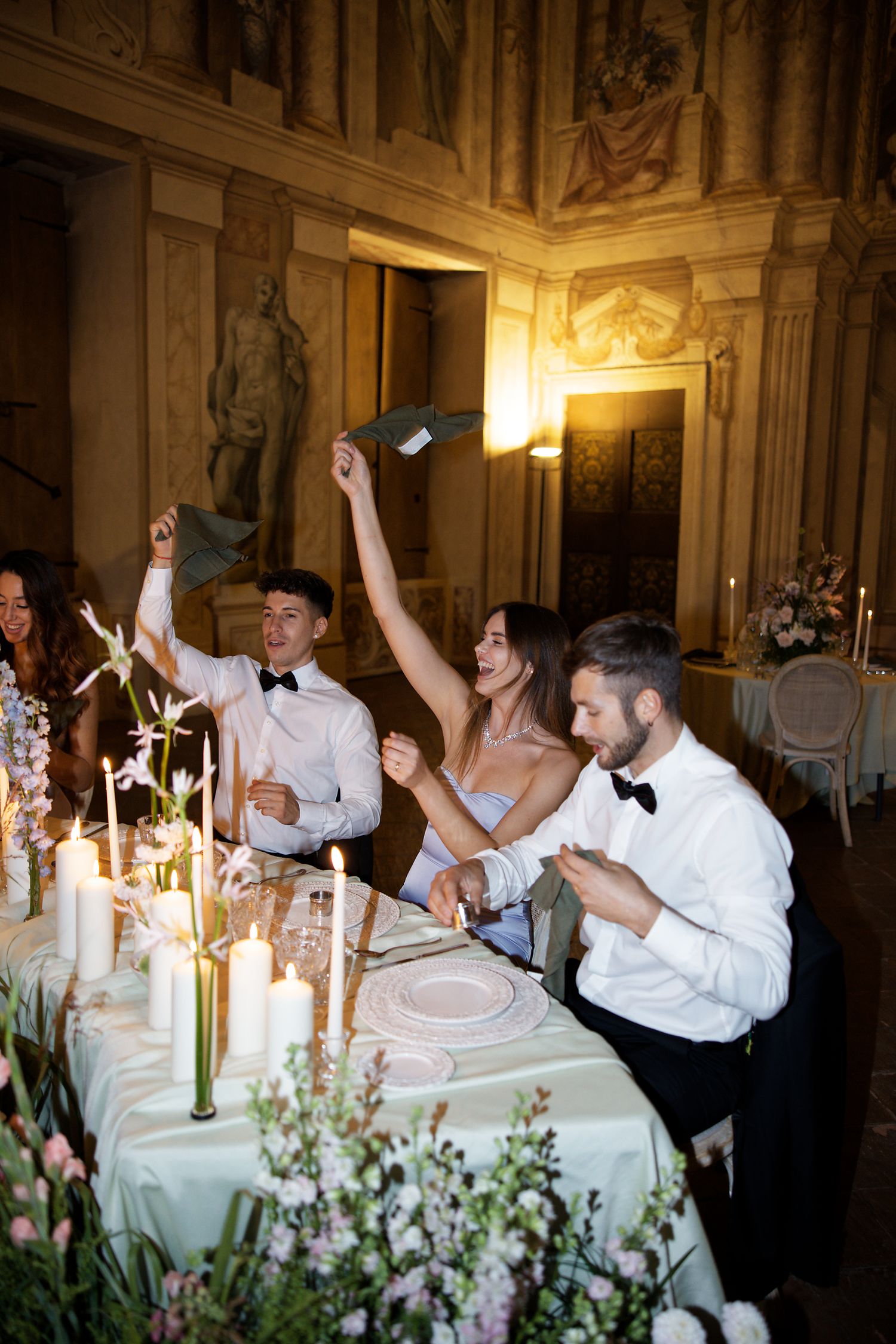 Guests celebrating with sparklers at an elegant candlelit reception dinner in an ornate venue.