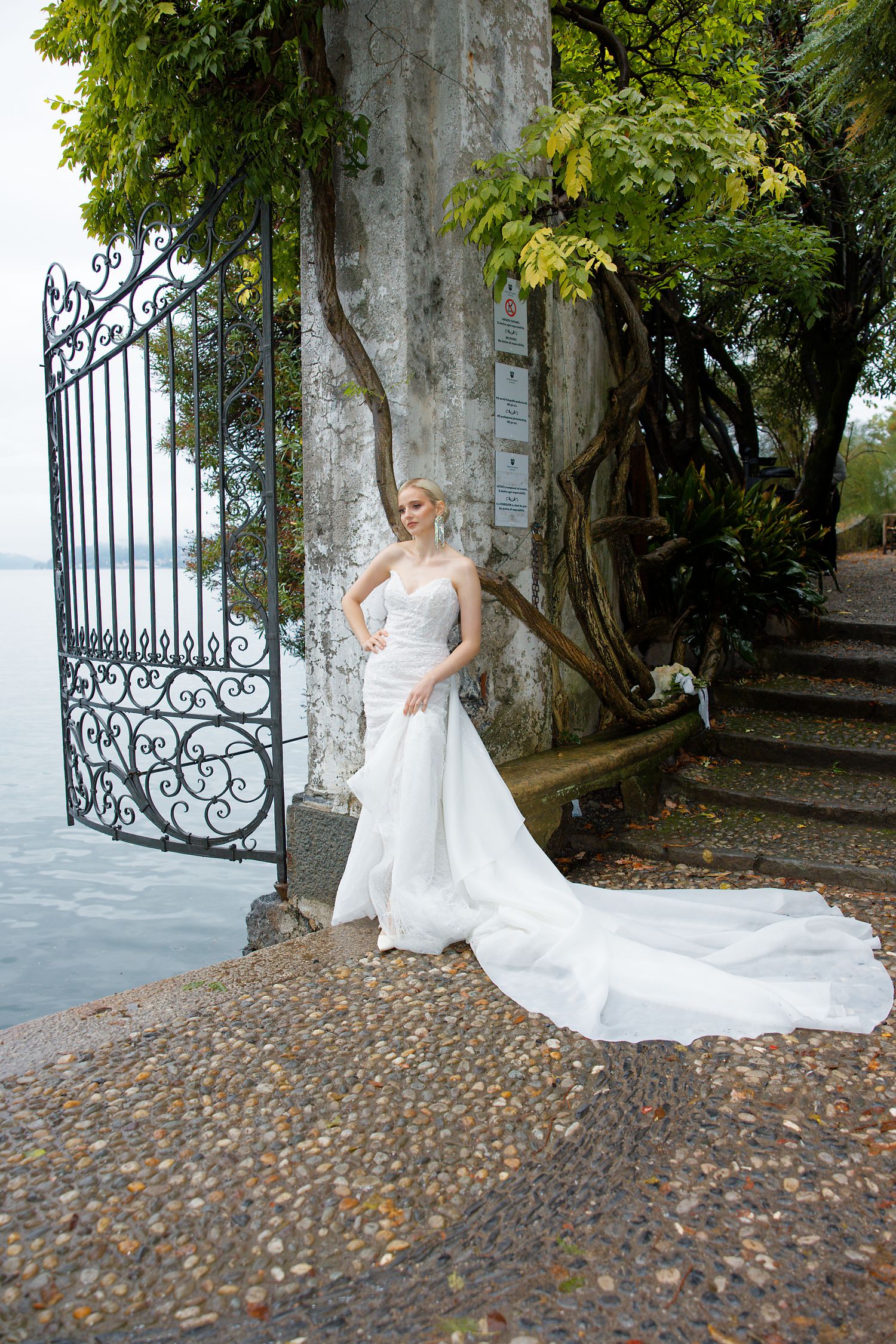 Elegant bridal portrait by ornate iron gates overlooking a lake.