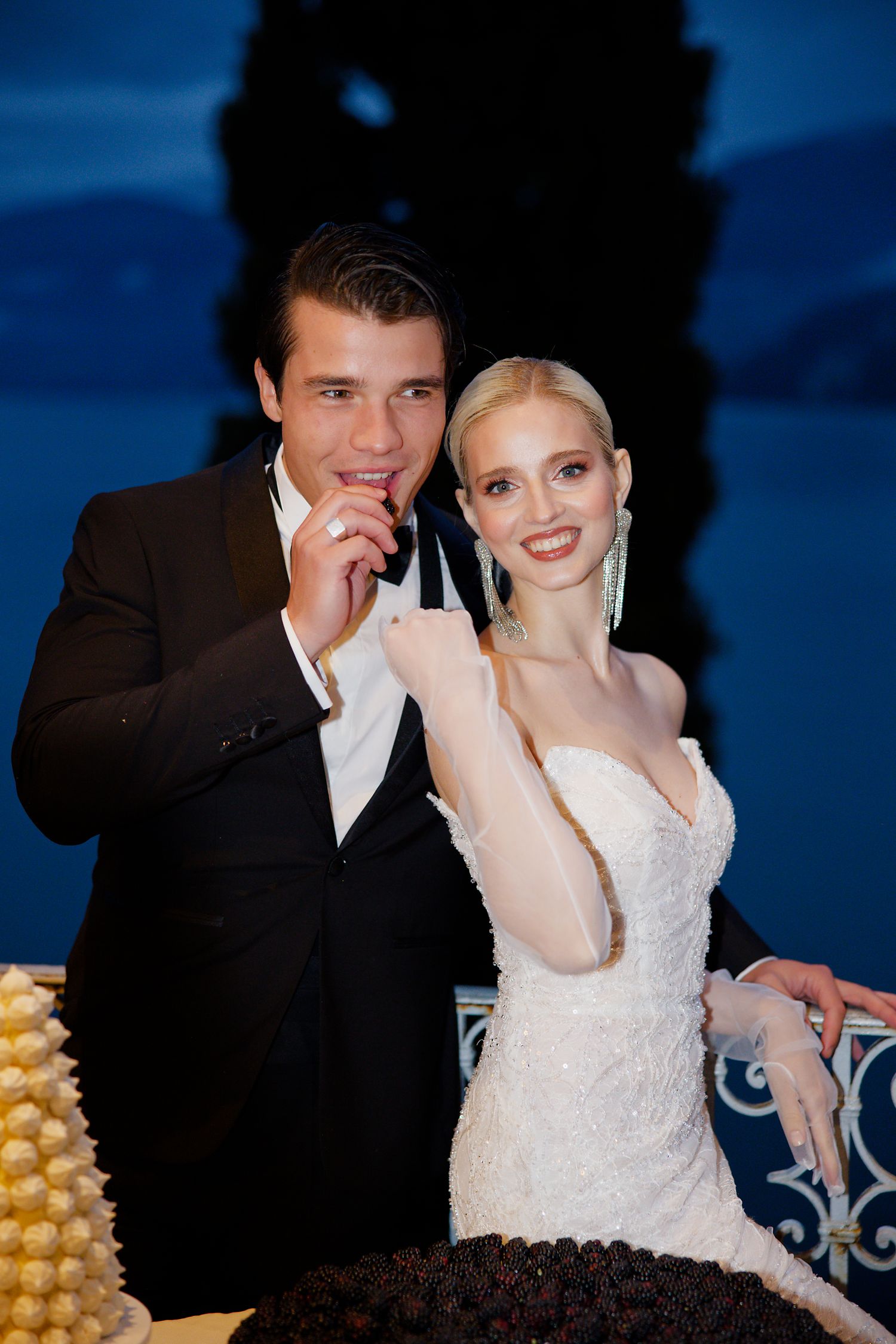 Elegant evening wedding reception with couple by dessert table.
