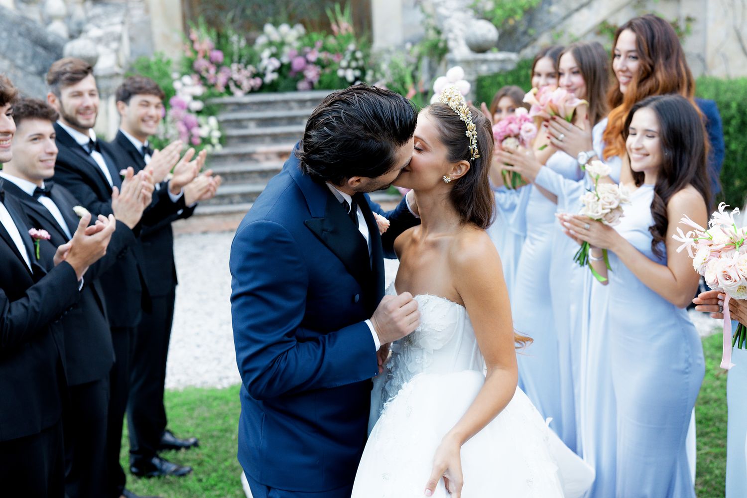 Wedding celebration in front of an elegant historic villa with grand staircase and garden backdrop.