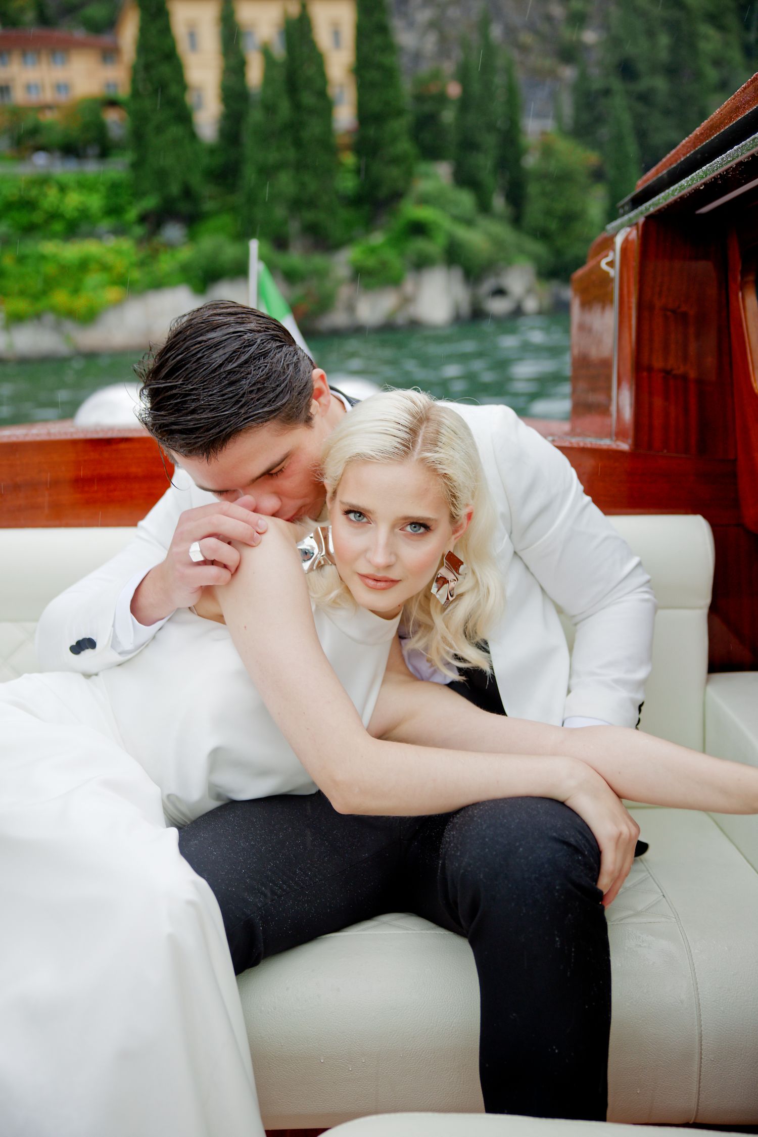 Wedding couple sharing intimate moment on luxury boat with Italian lake scenery.
