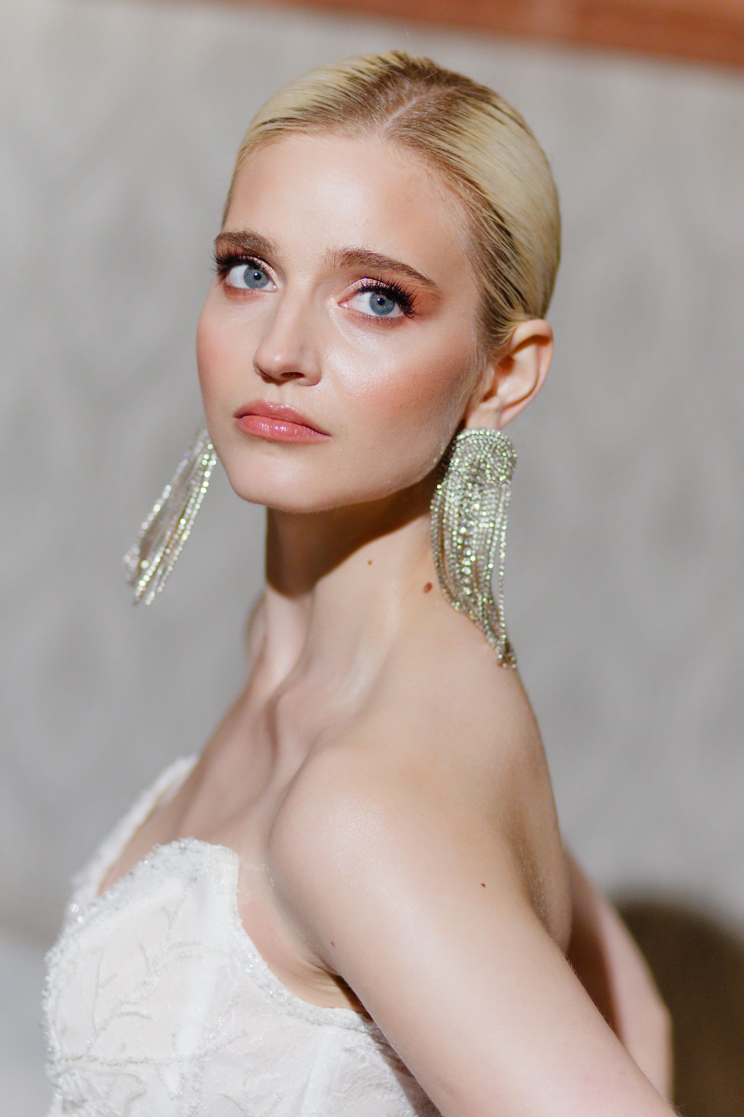 Bridal beauty portrait showcasing sparkling drop earrings and elegant makeup.