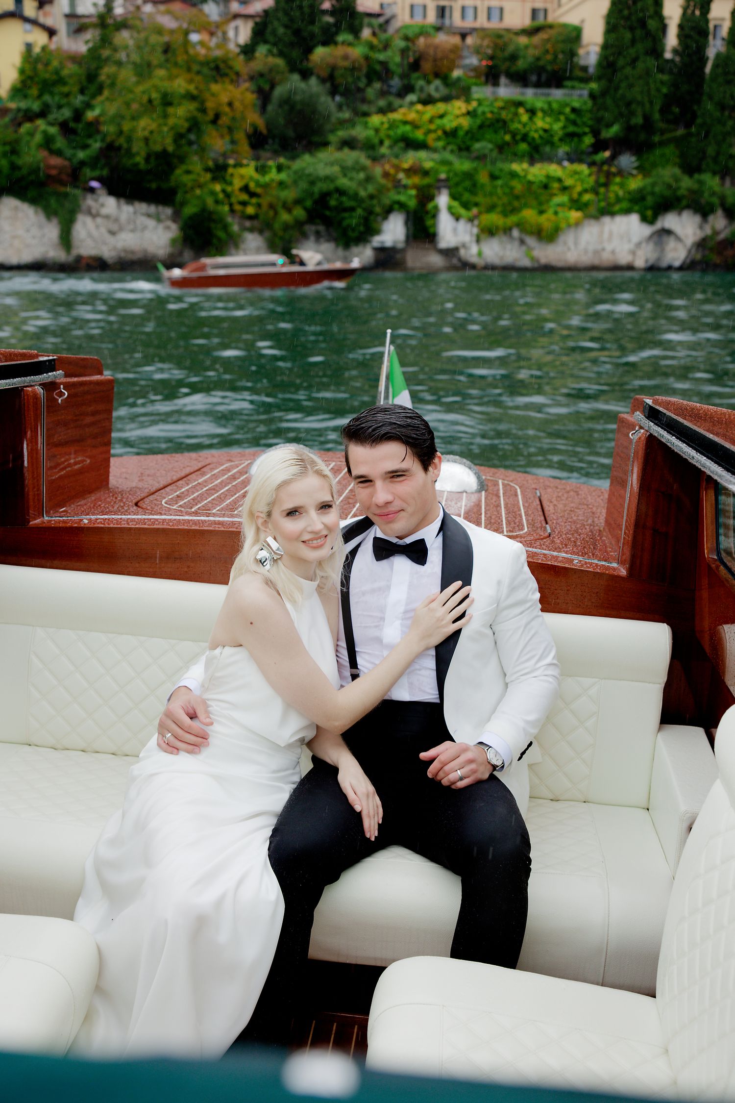 Newlyweds share intimate moment on classic wooden boat on Italian lake.