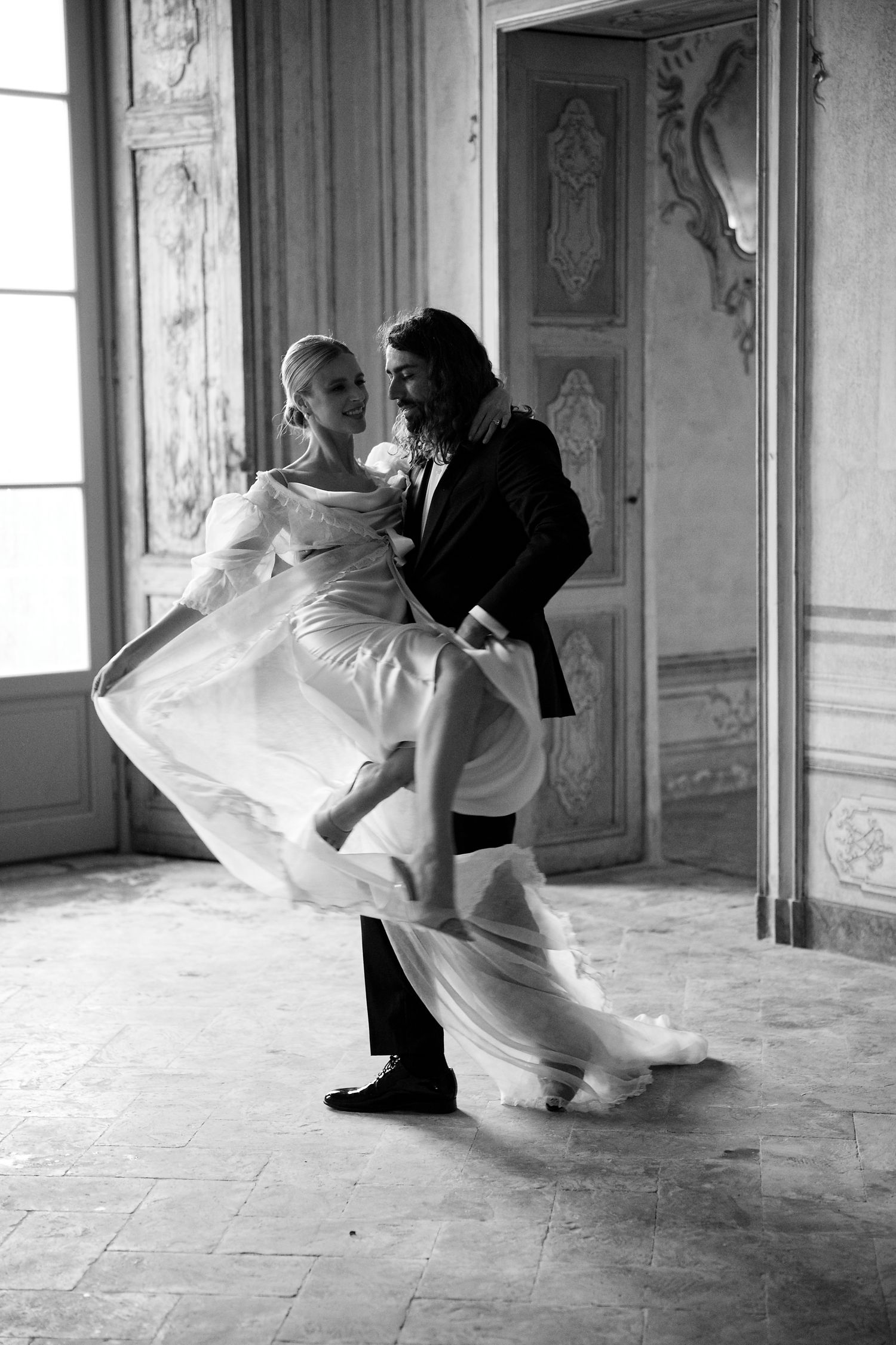 Black and white dance photo showing dramatic movement of white dress in historic interior.