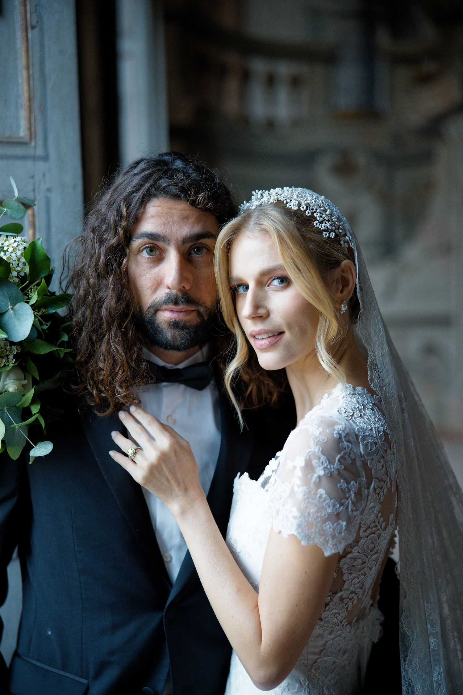 A wedding portrait of a couple in formal attire against an elegant backdrop.